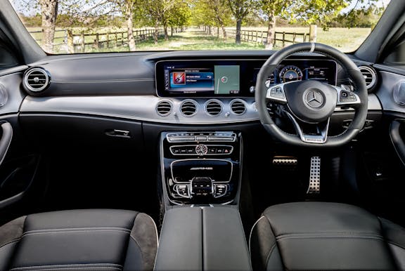 The interior of a Mercedes-Benz E-Class with steering wheel and dashboard in shot