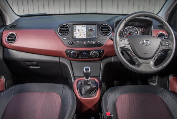 The interior of an Hyundai i10 with steering wheel and dashboard in shot