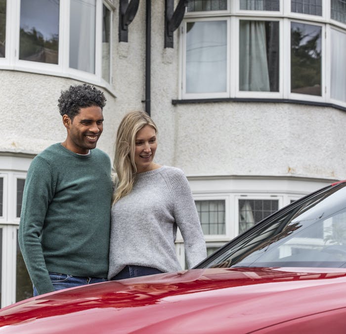 Happy couple looking at their new car from Cazoo