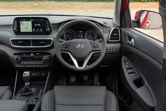 The interior of a Hyundai Tucson with steering wheel and dashboard in shot