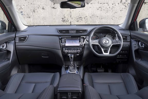 The interior of a Nissan X-Trail with steering wheel and dashboard in shot
