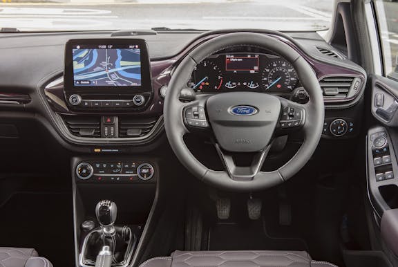 The interior of a Ford Fiesta with steering wheel and dashboard in shot