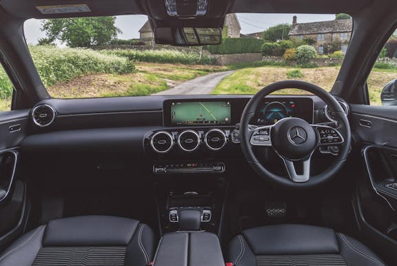 The interior of a Mercedes-Benz A-Class with steering wheel and dashboard in shot