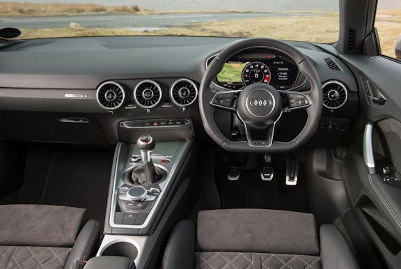 The interior of an Audi TT with steering wheel and dashboard in shot