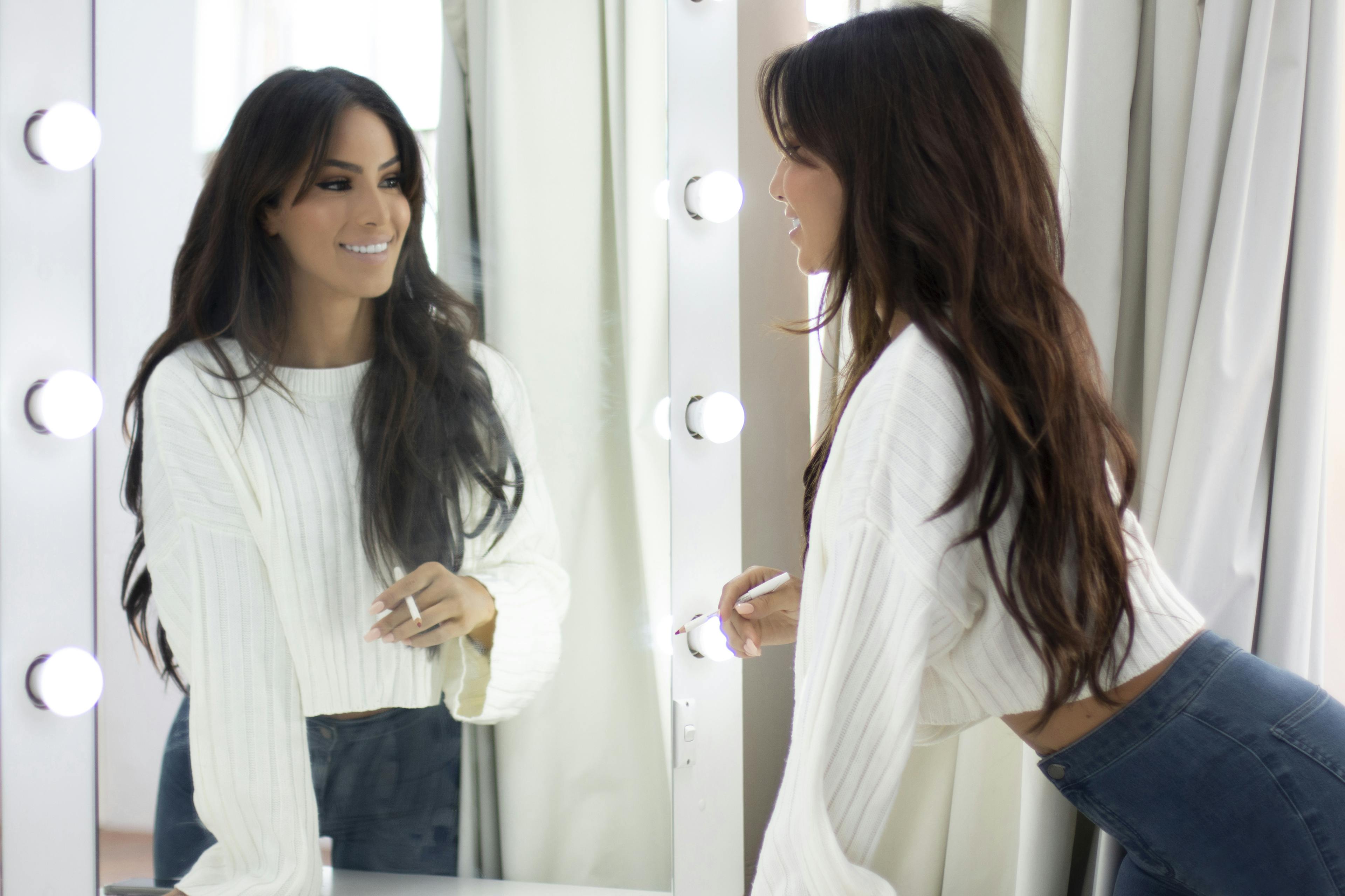 Christina Sikalias looking in mirror at new smile with Picasso Porcelain Veneers.