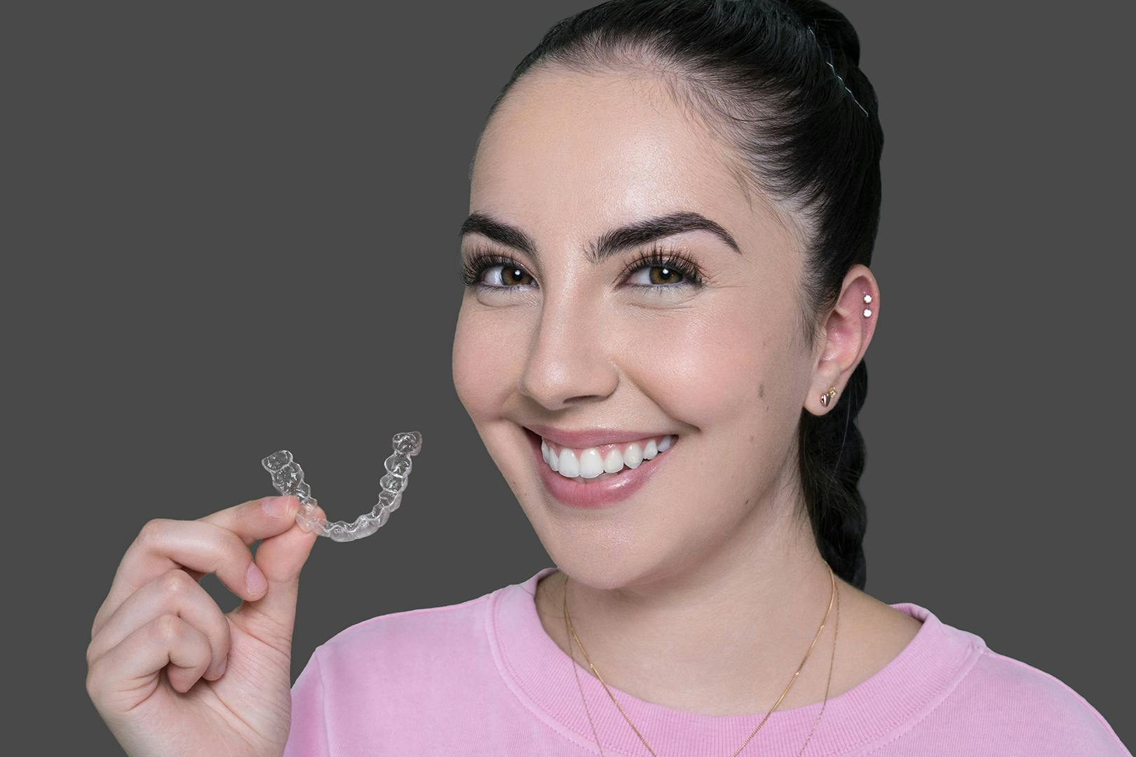 Emily from Vogue Dental Studios holding Invisalign clear aligners.