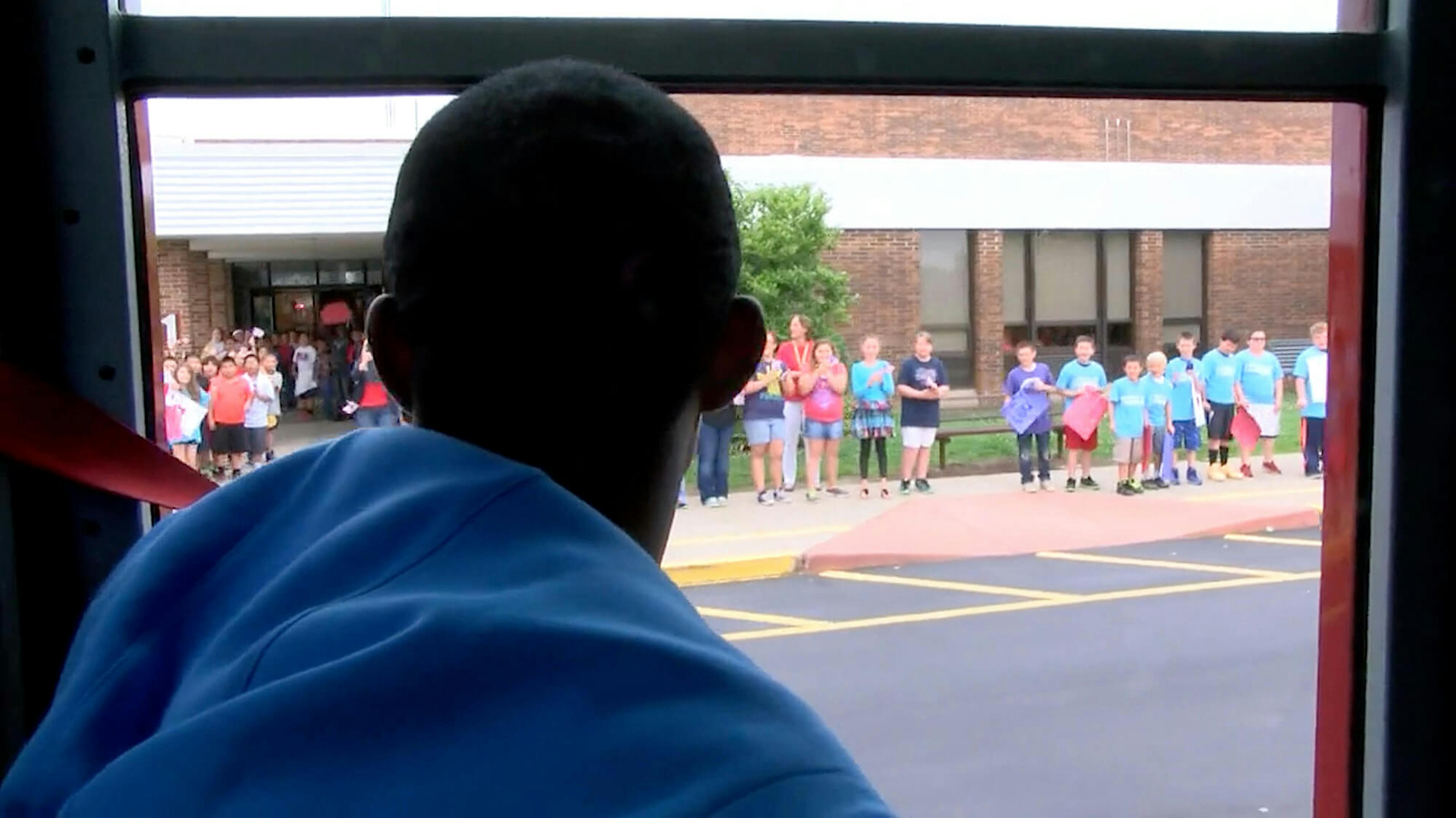 Lex Gillette arrives at a school while students wait to greet him