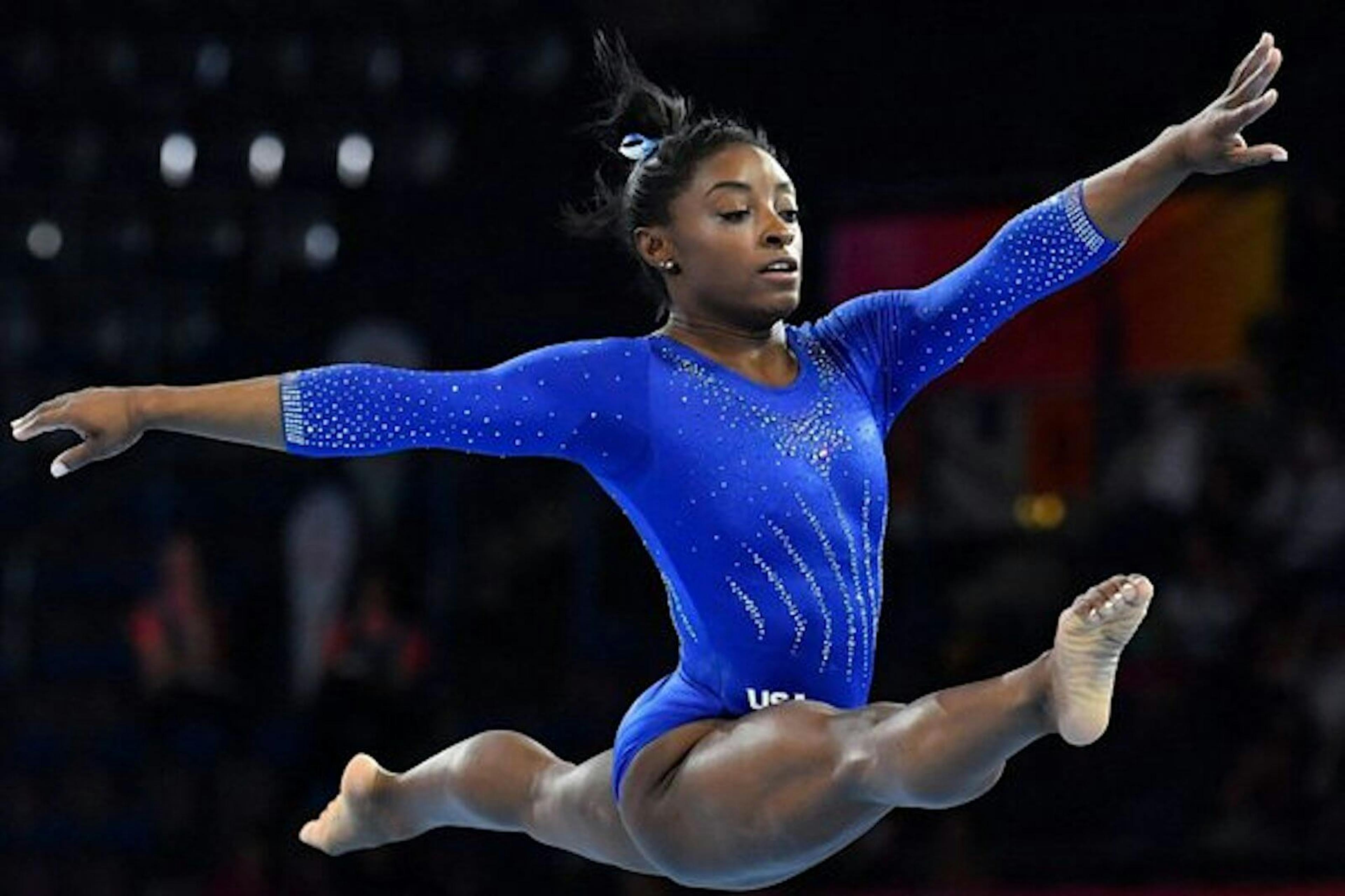 Simone Biles jumping in a blue uniform