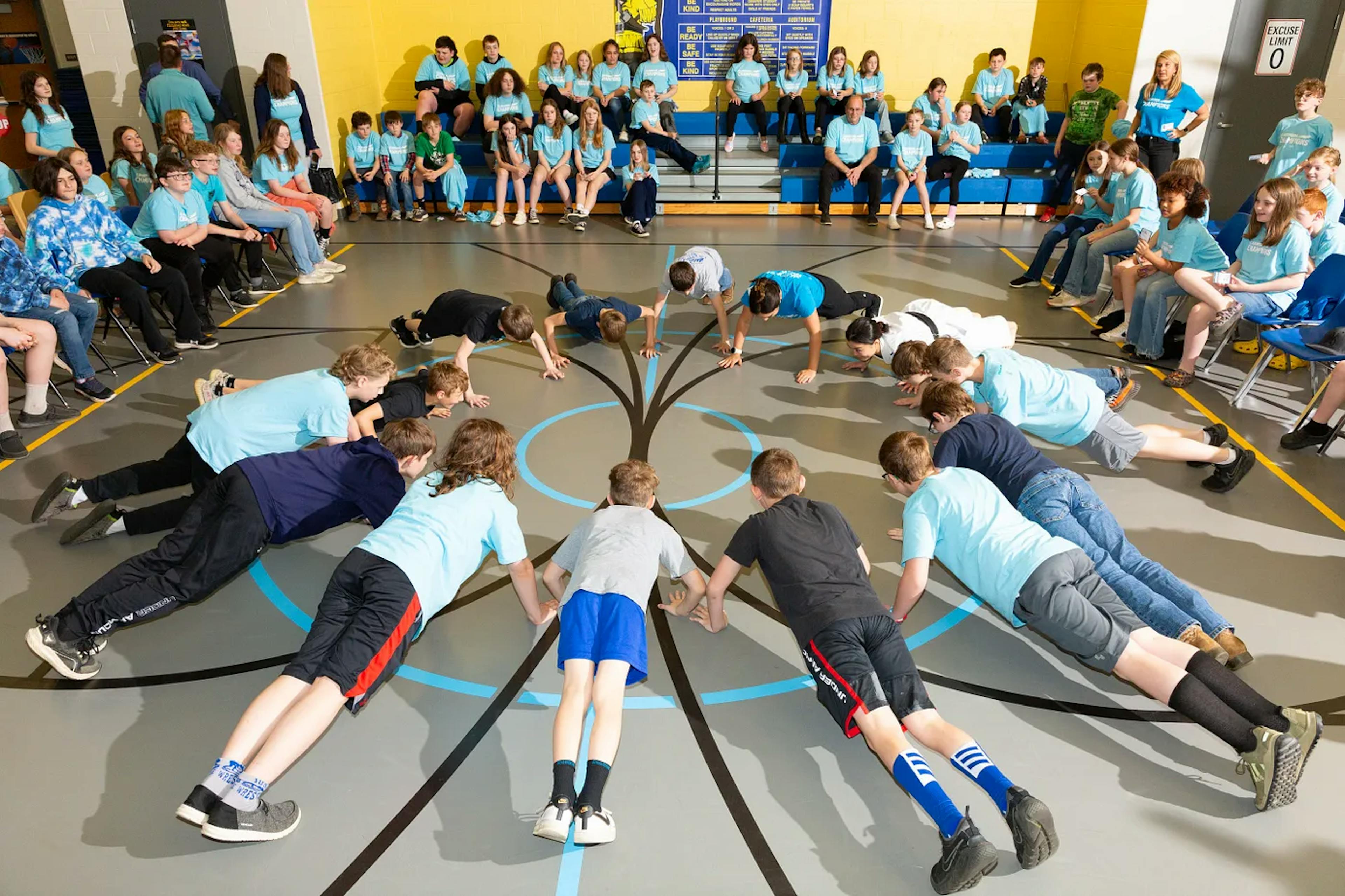 A group of students doing pushups in a gym.