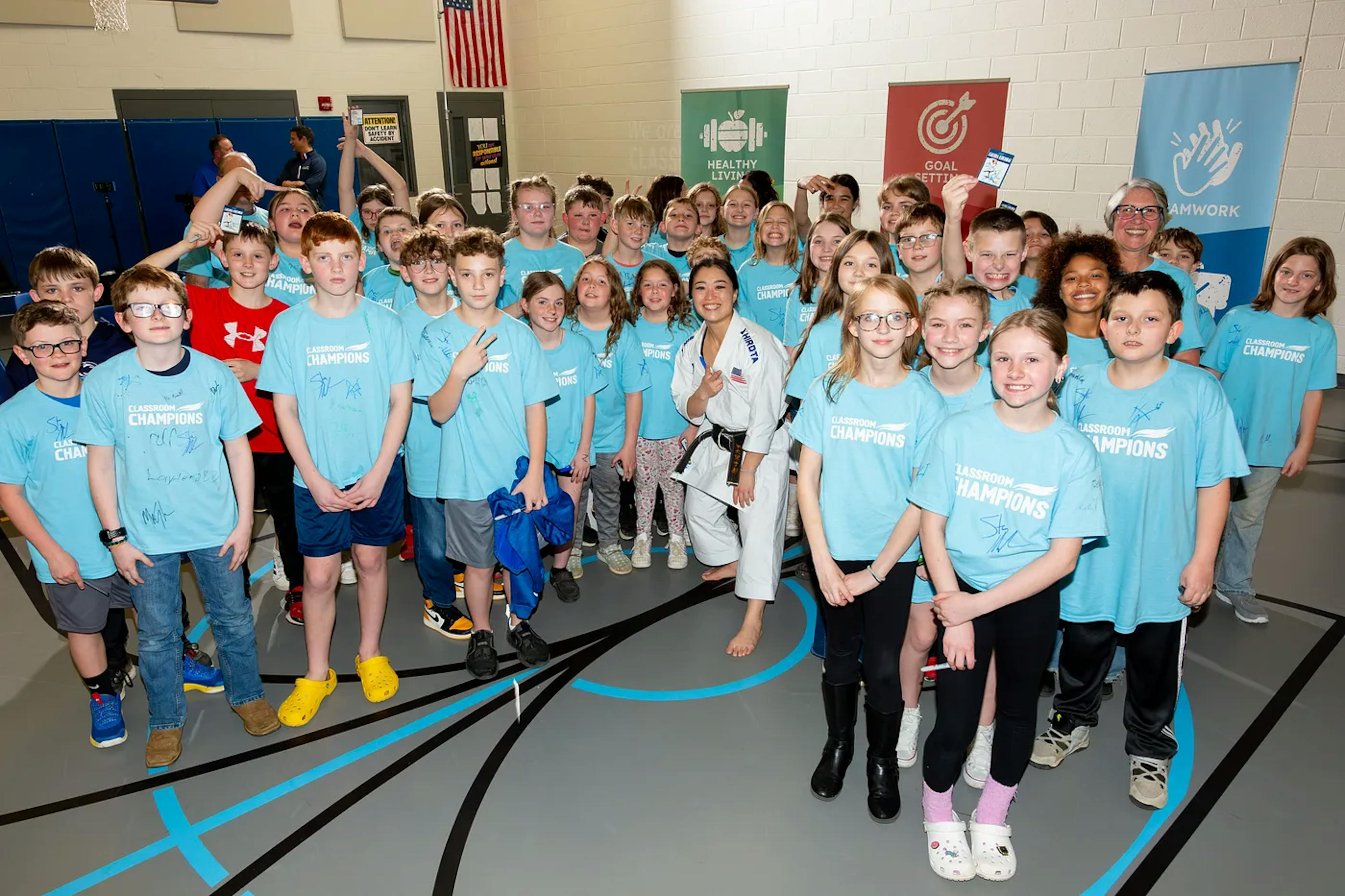 A group of kids in Classroom Champions shirts smile for a class photo