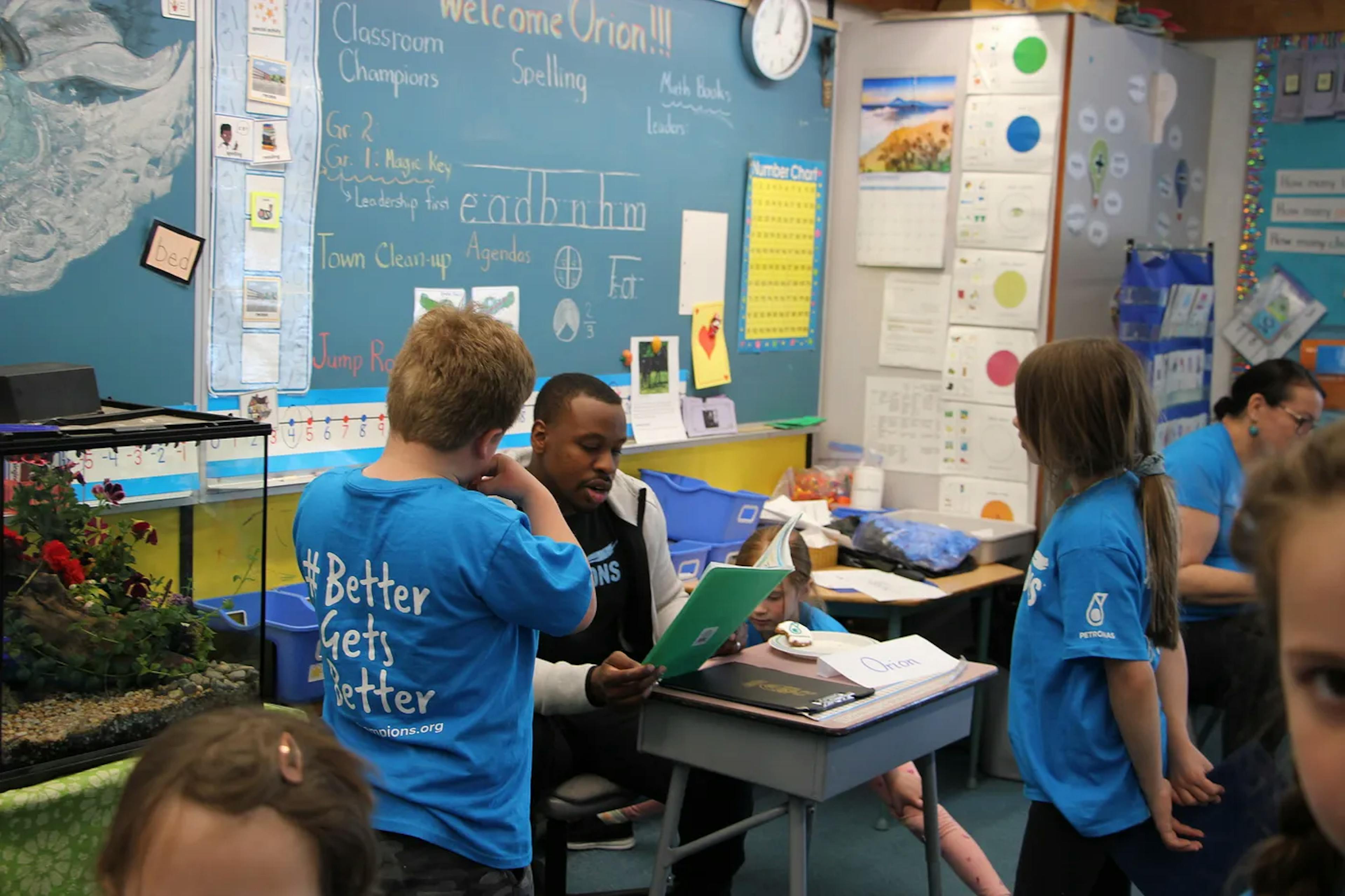 Students participating in Classroom Champions chat with an athlete in a classroom.