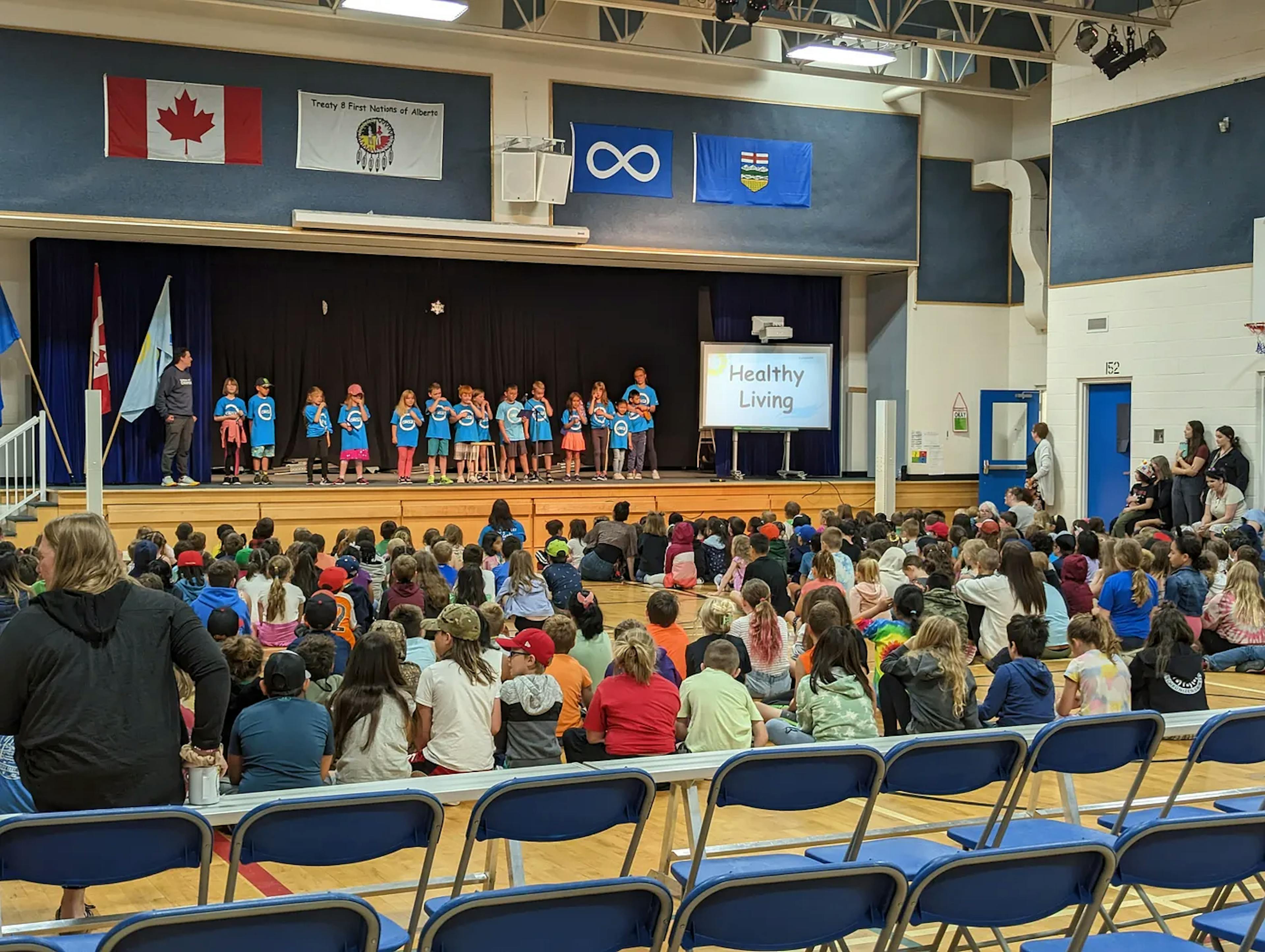 Gymnasium with students presenting on stage