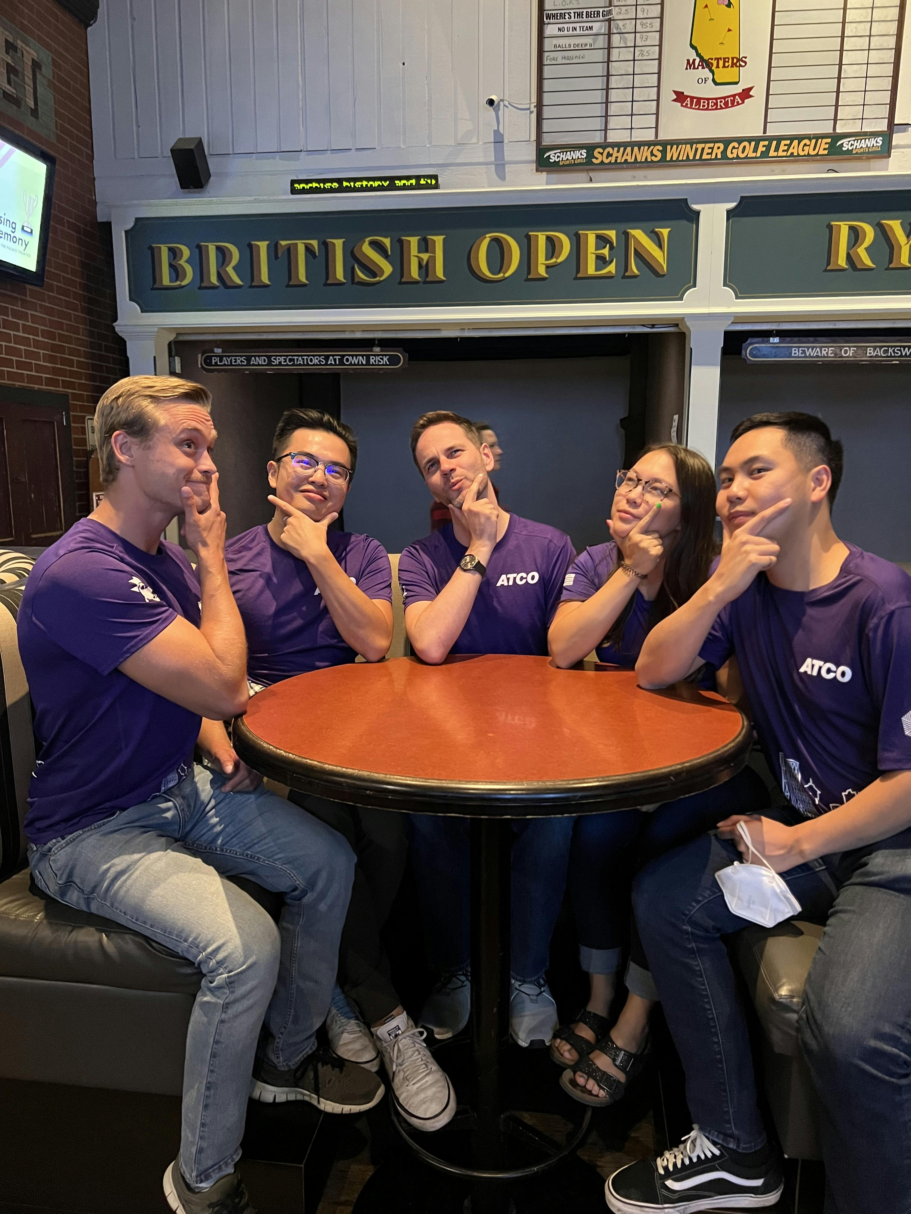 group of 5 people in purple shirts in a thinking pose