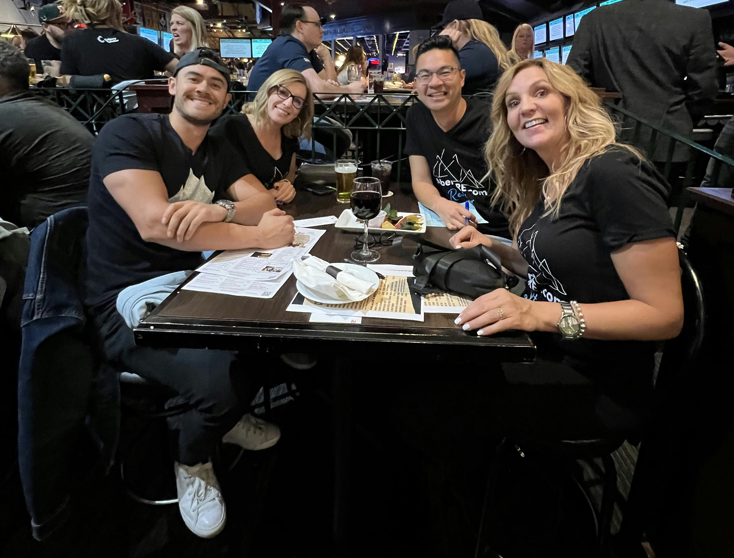group of 4 people in black shirts at a trivia event smiling