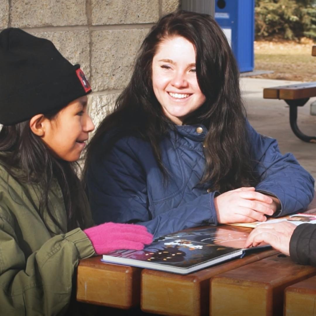 a mentor and mentee smiling at a picnic table