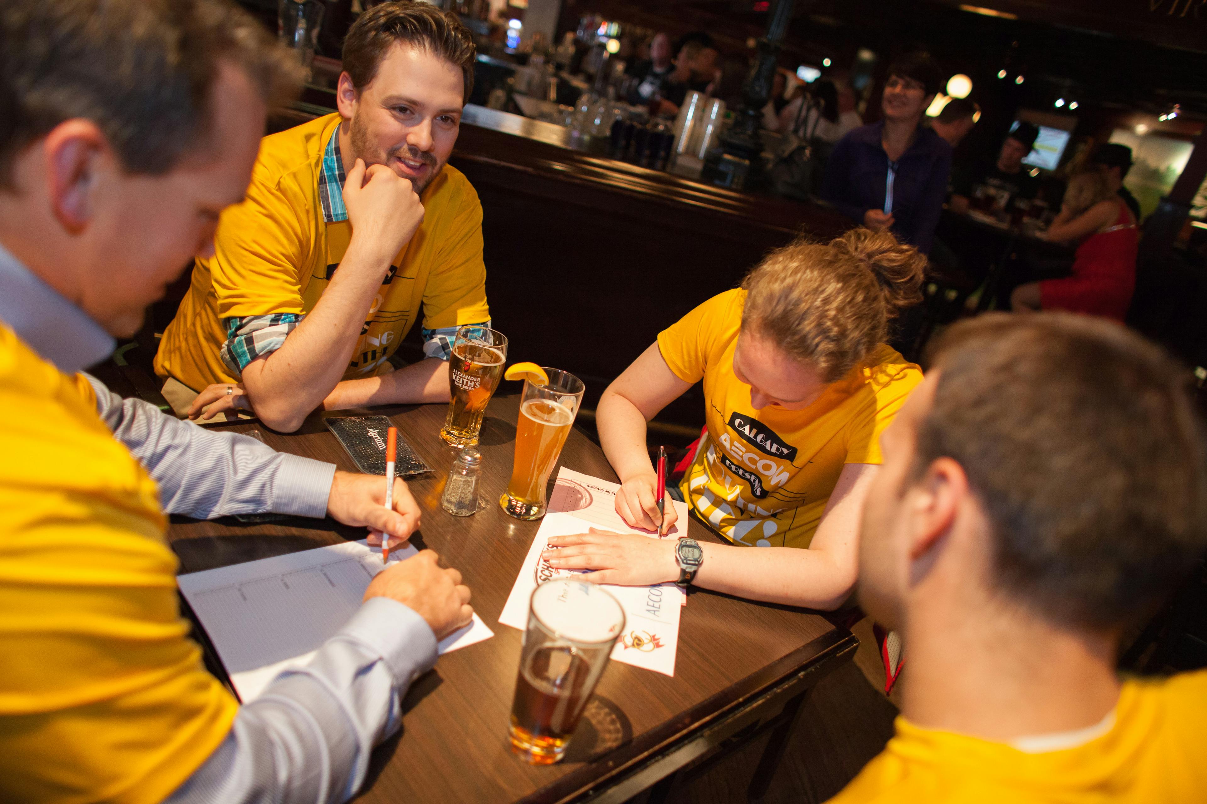 A group of four people in yellow shirts, playing trivia