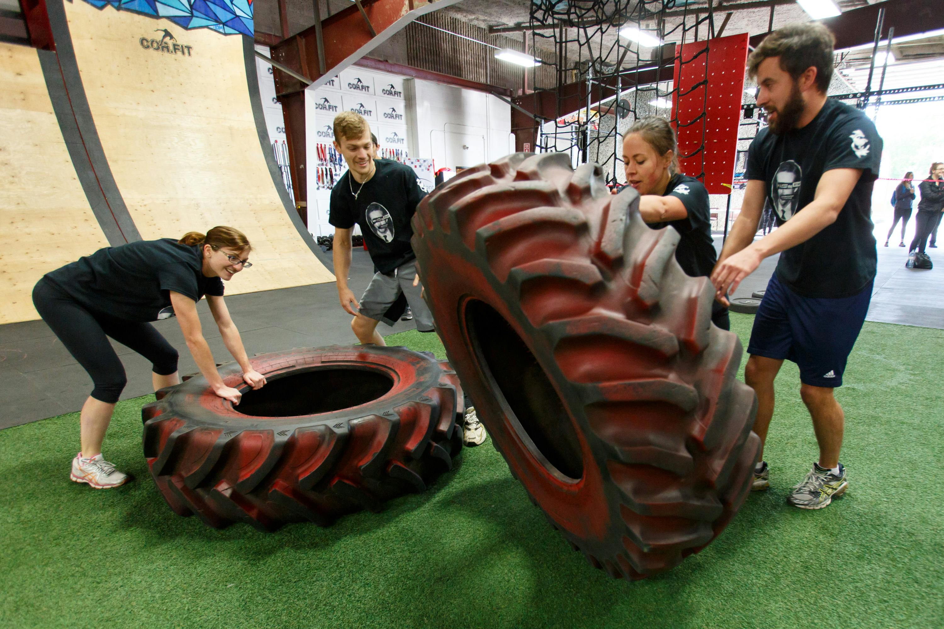 Team of 4 flip heavy tires in the obstacle course race event