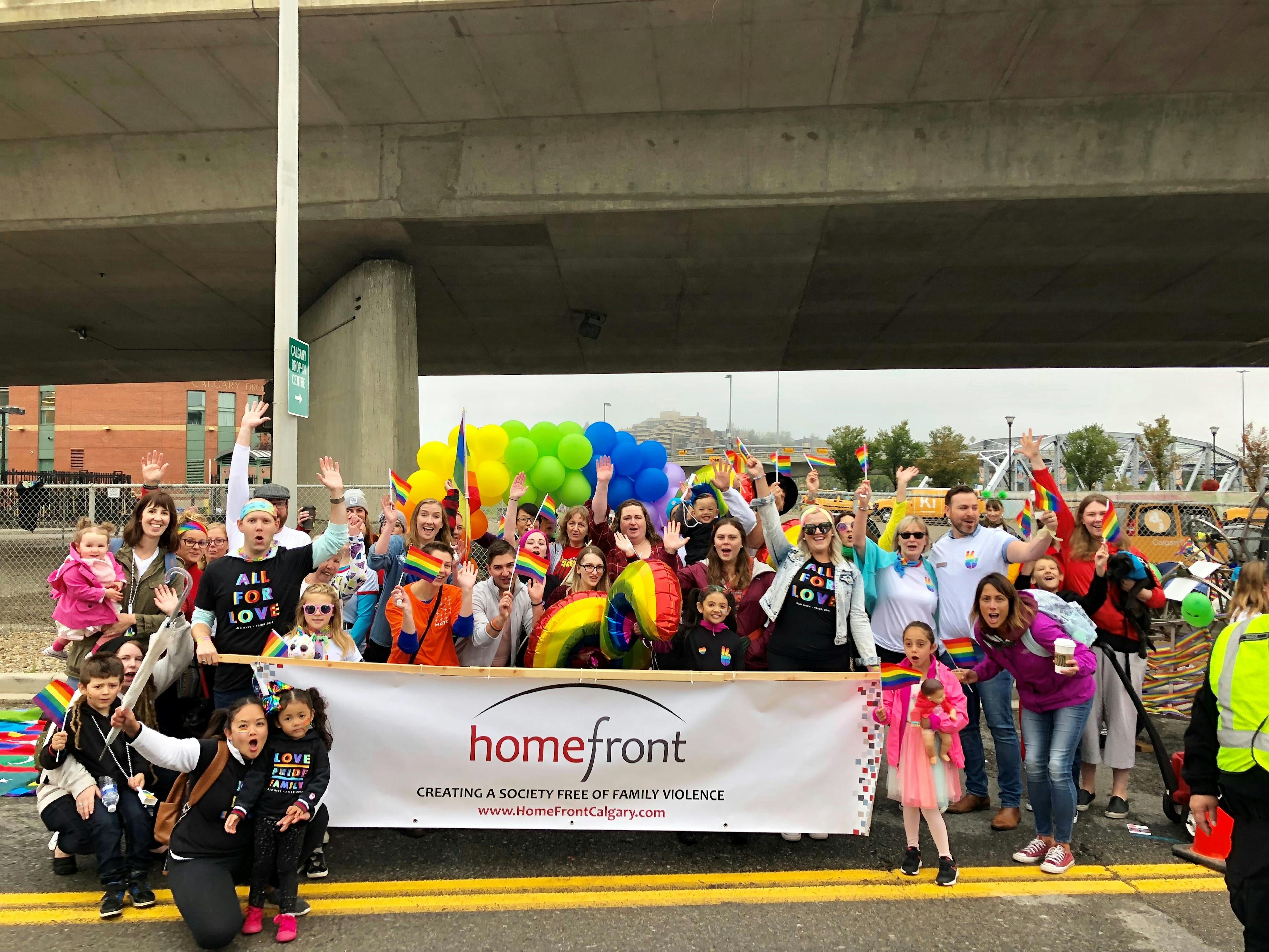 A large group of people holding a Homefront banner, celebrating Pride