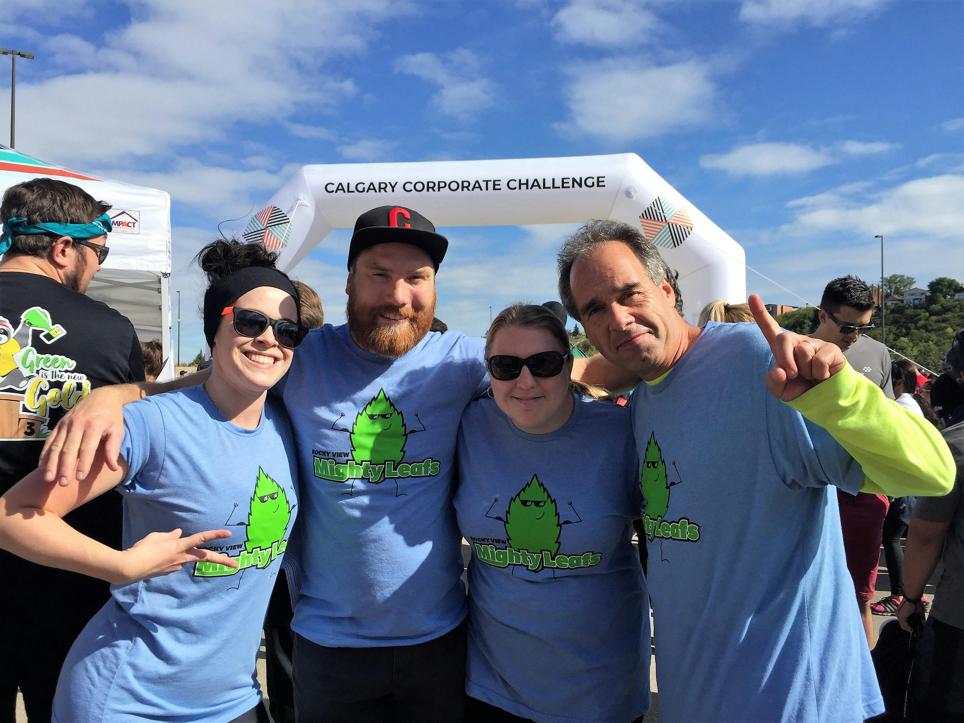 Four people smiling in front of ccc race arch