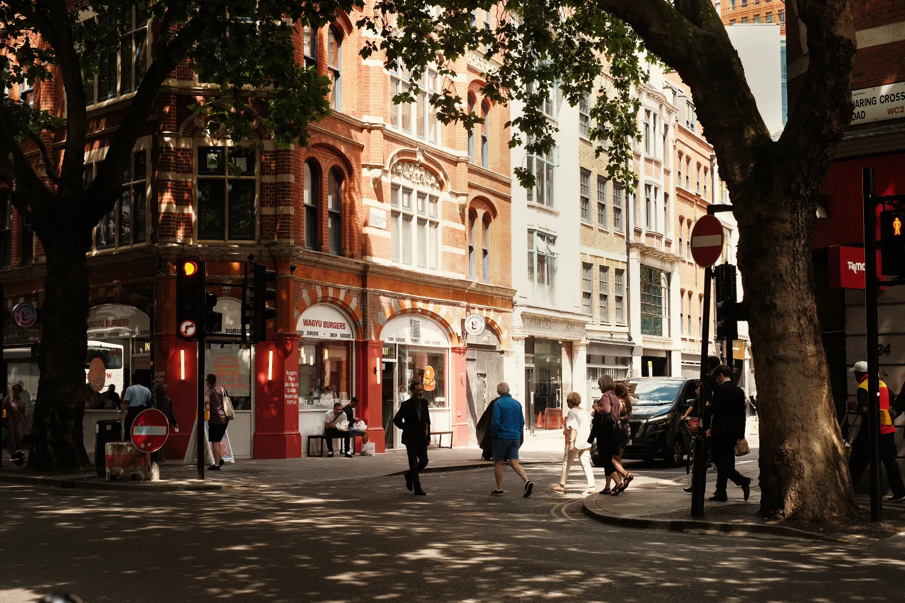 Pedestrians on a tree-lined London street in evening sunshine