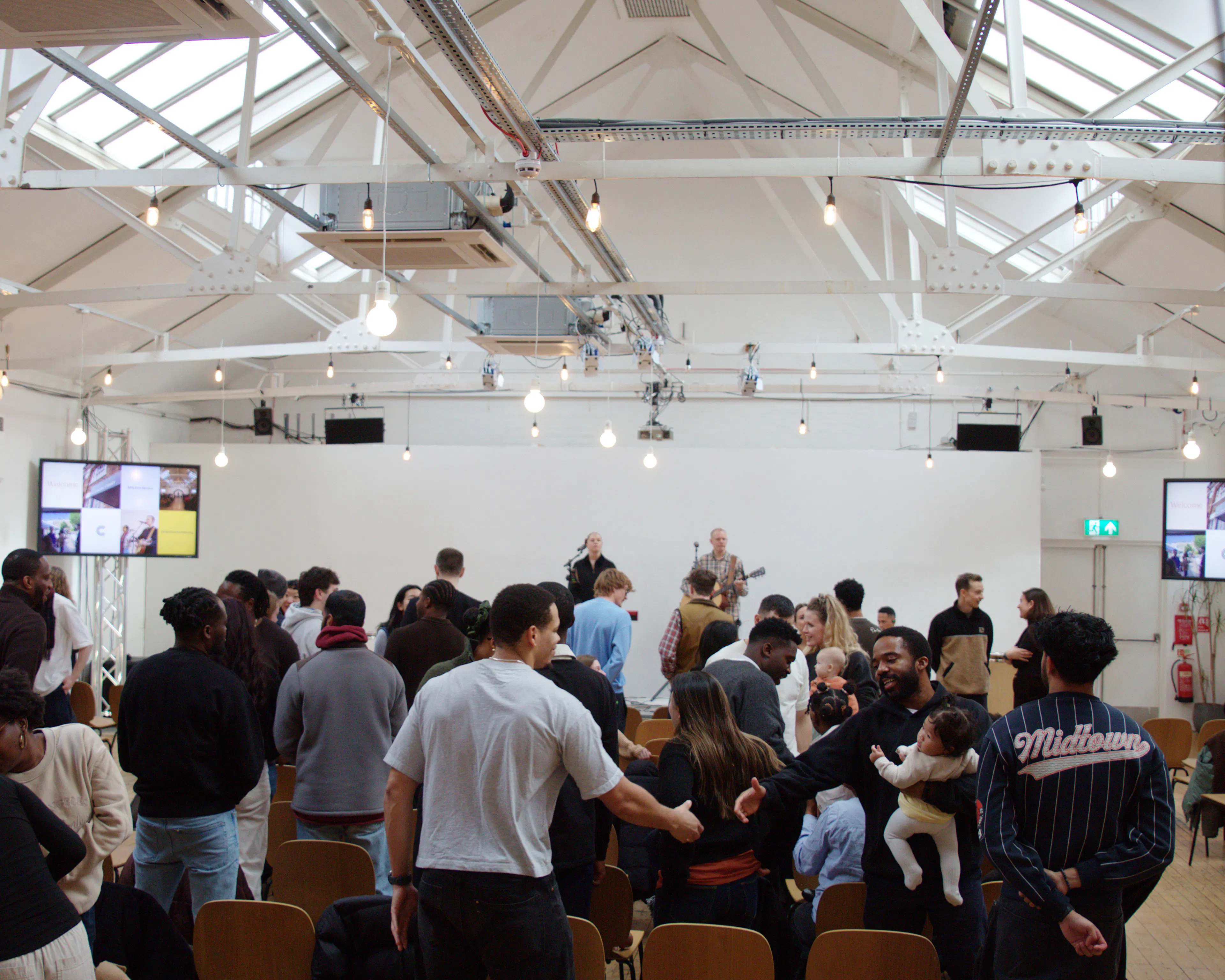 Congregation standing in worship in a large hall with skylights