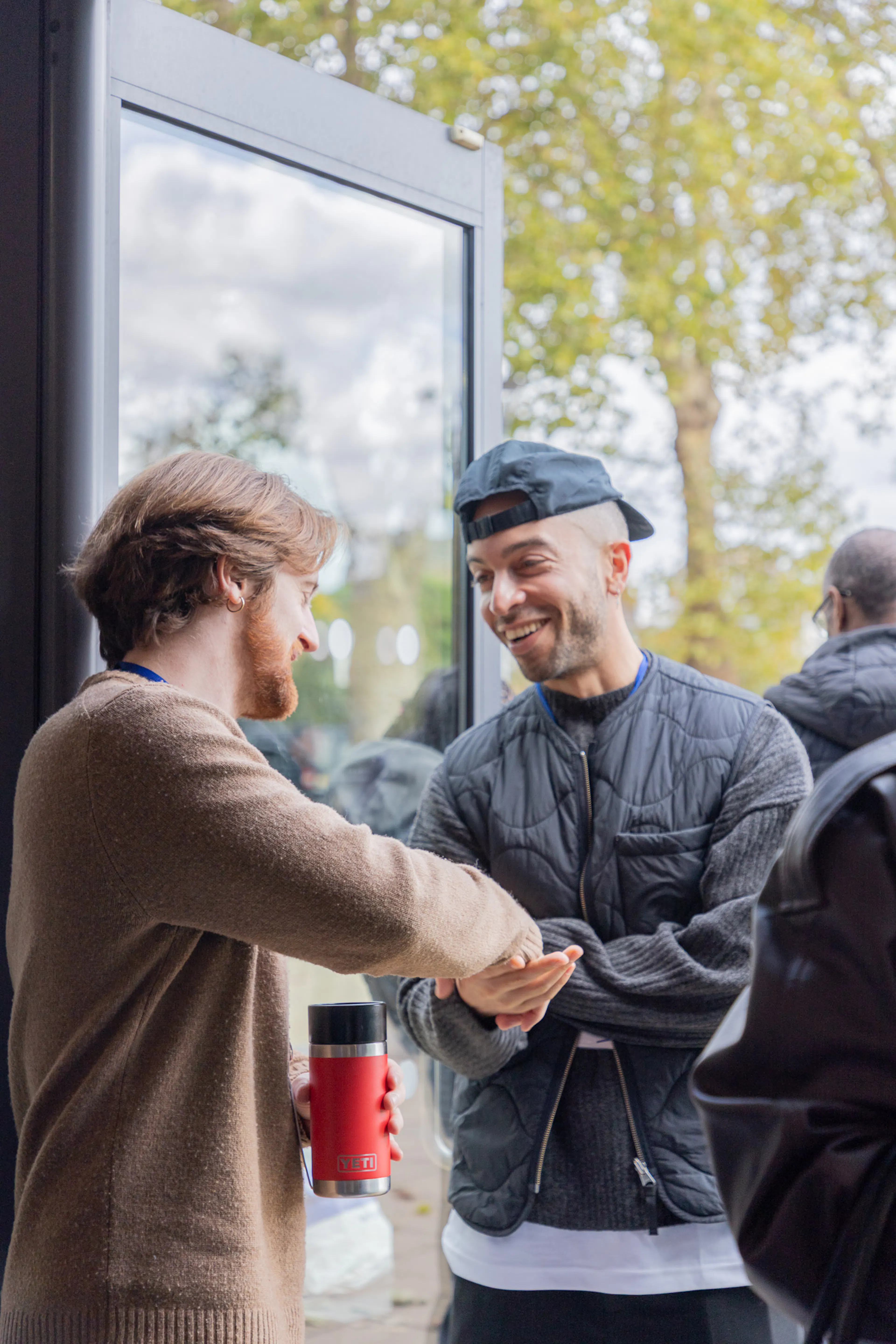 Two men greeting each other with a handshake outside a church entrance