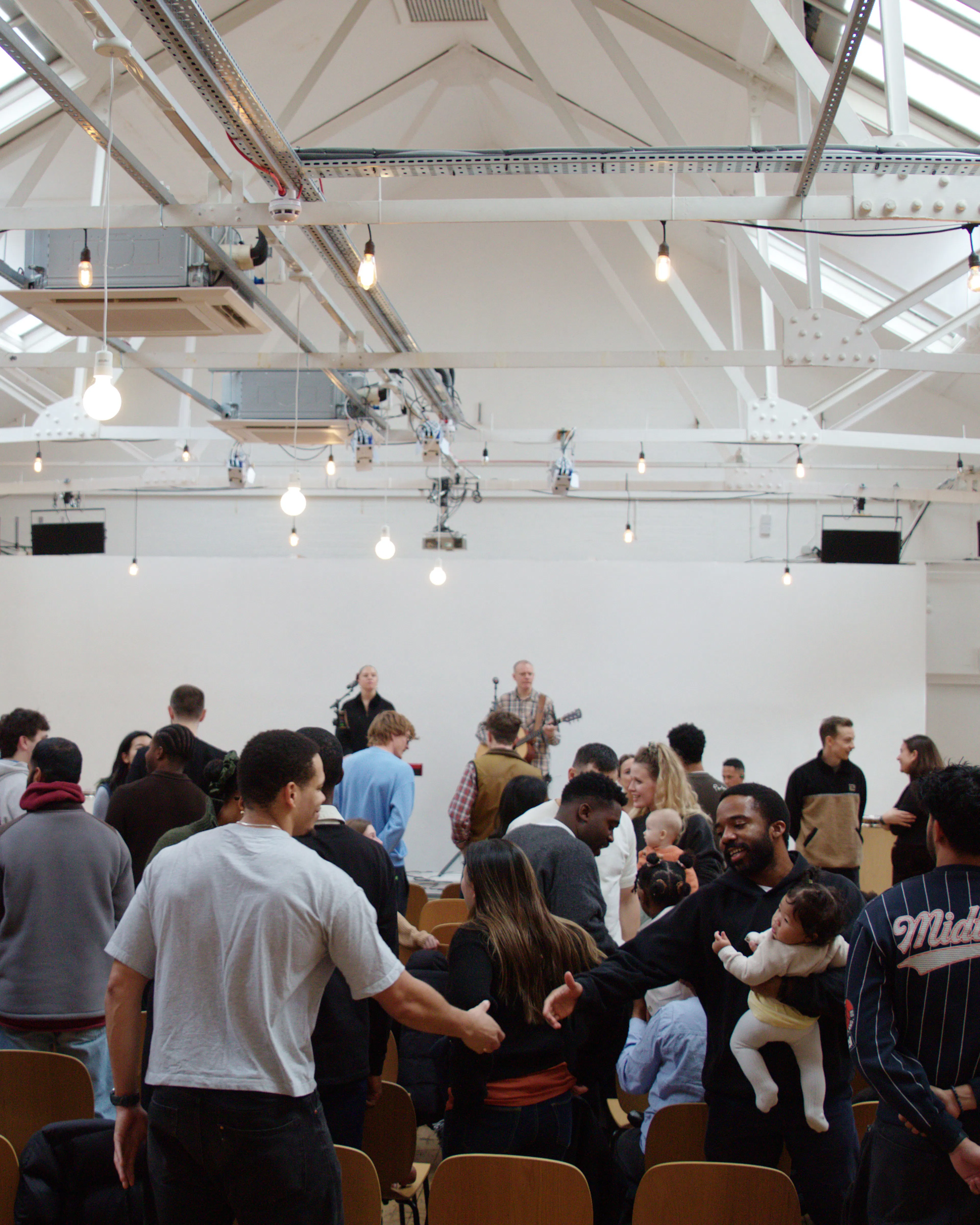 Congregation standing in worship in a large hall with skylights