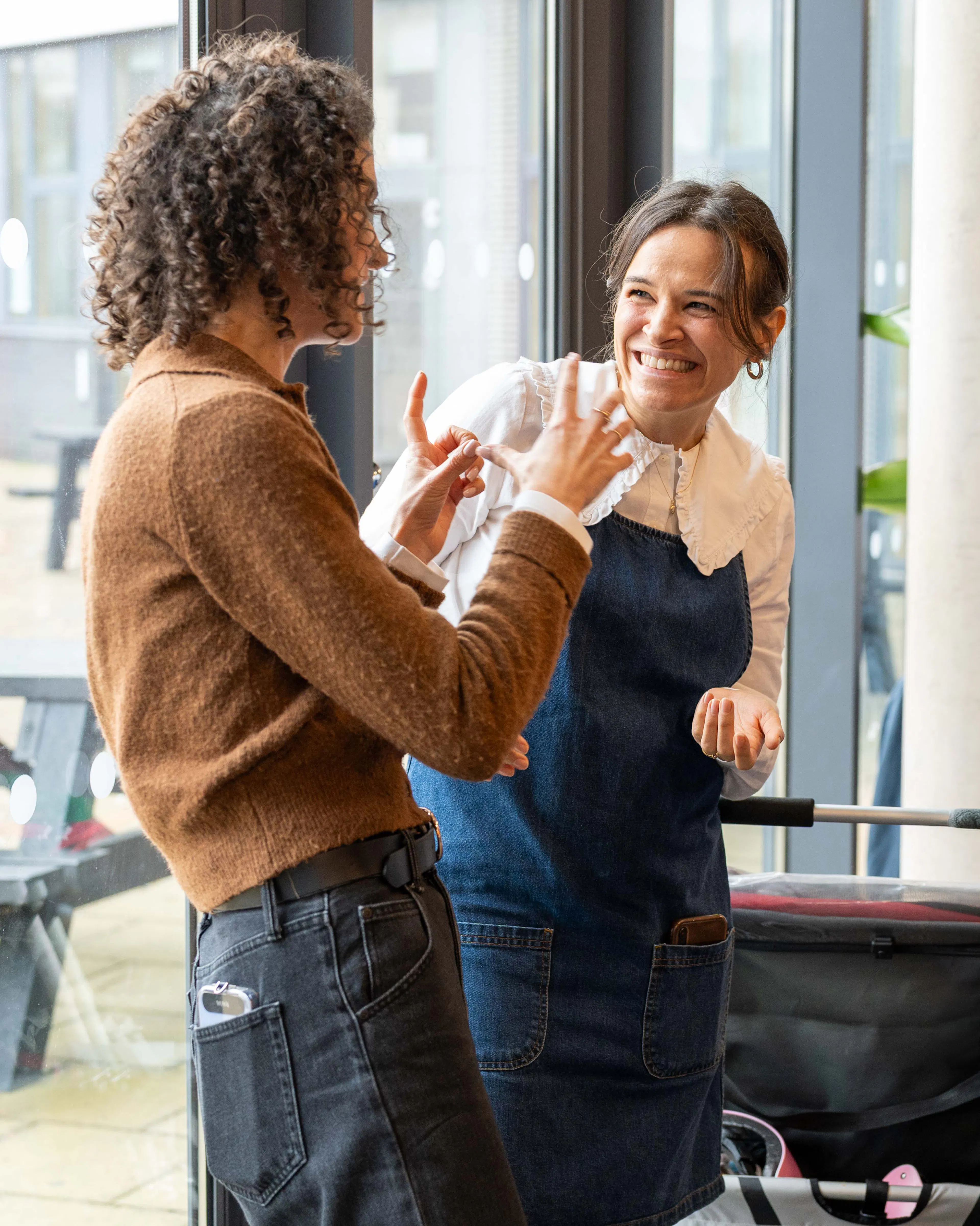 Two women chatting and laughing by a window