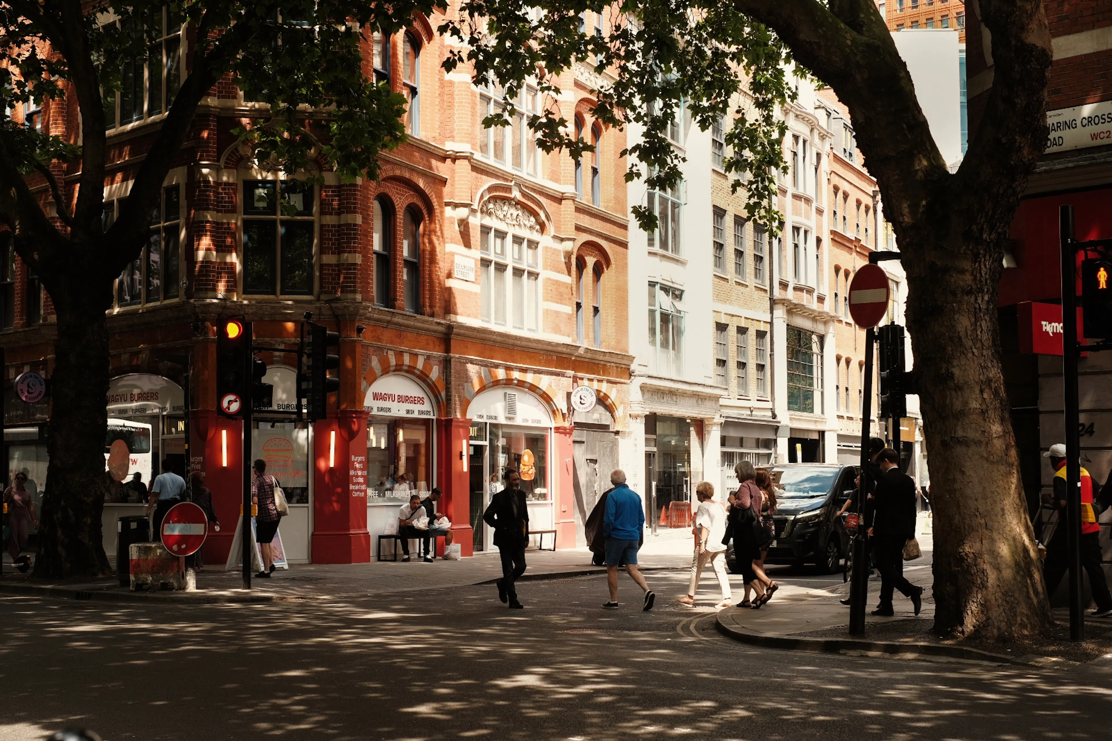 Pedestrians on a tree-lined London street in evening sunshine