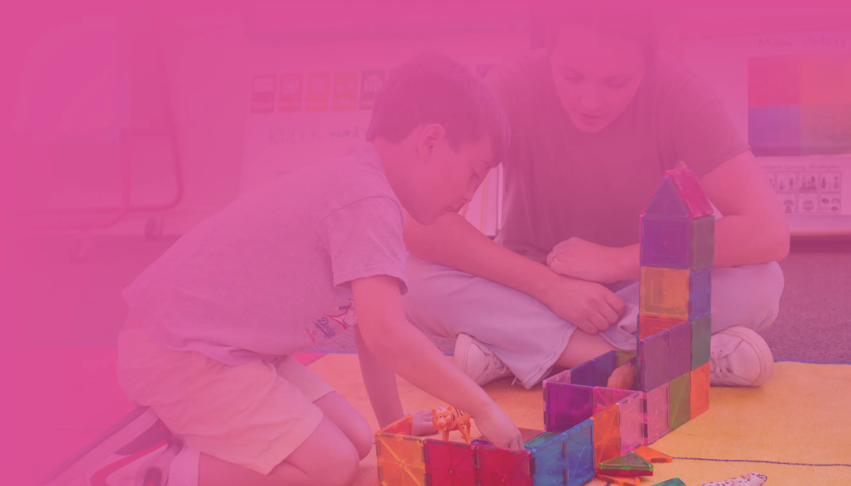 Teacher guiding an early learner through building blocks. 