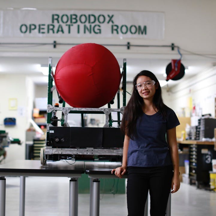 Girl standing in front of a machine. Sign in background that reads: "Robodox operating room".