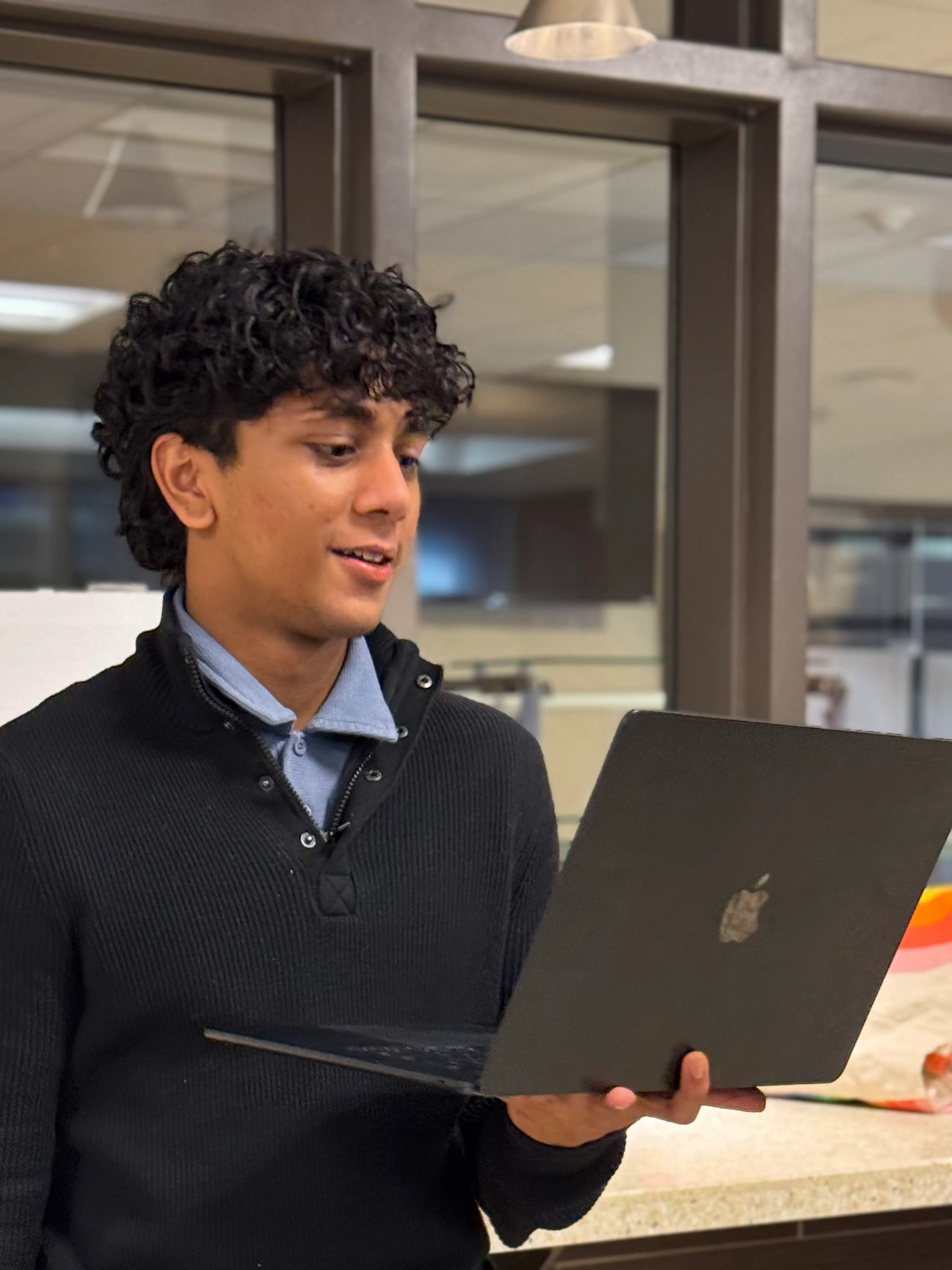 A student reading from a laptop delivers a speech