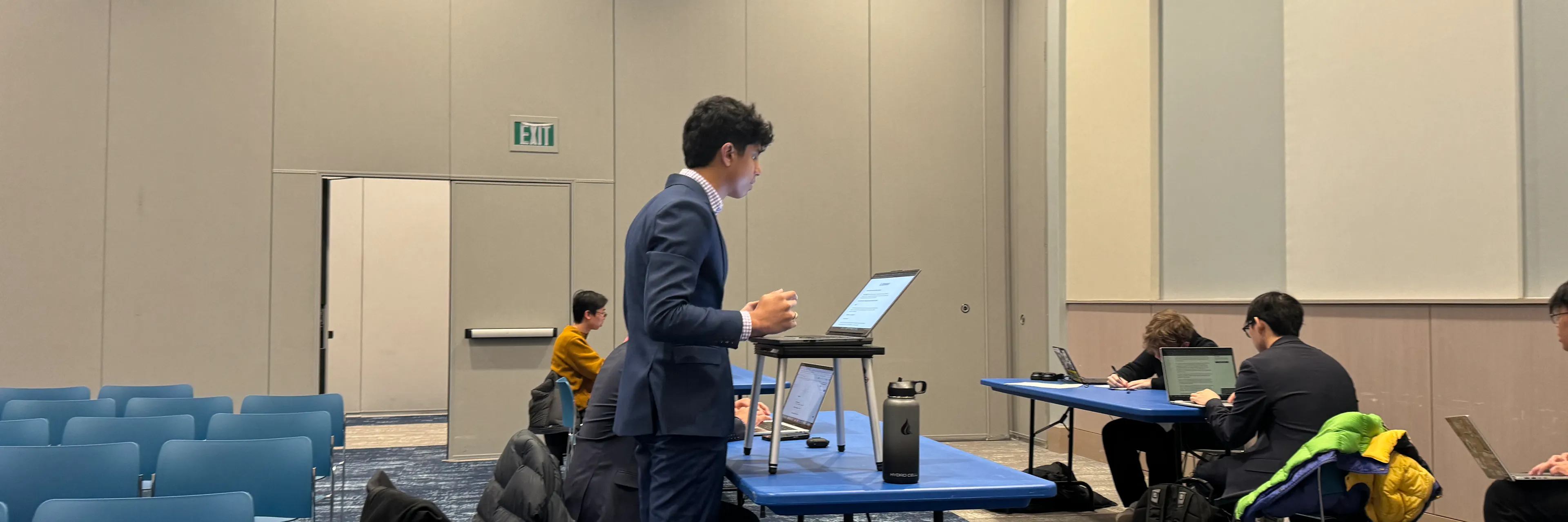 A student stands with a laptop and delivers a speech