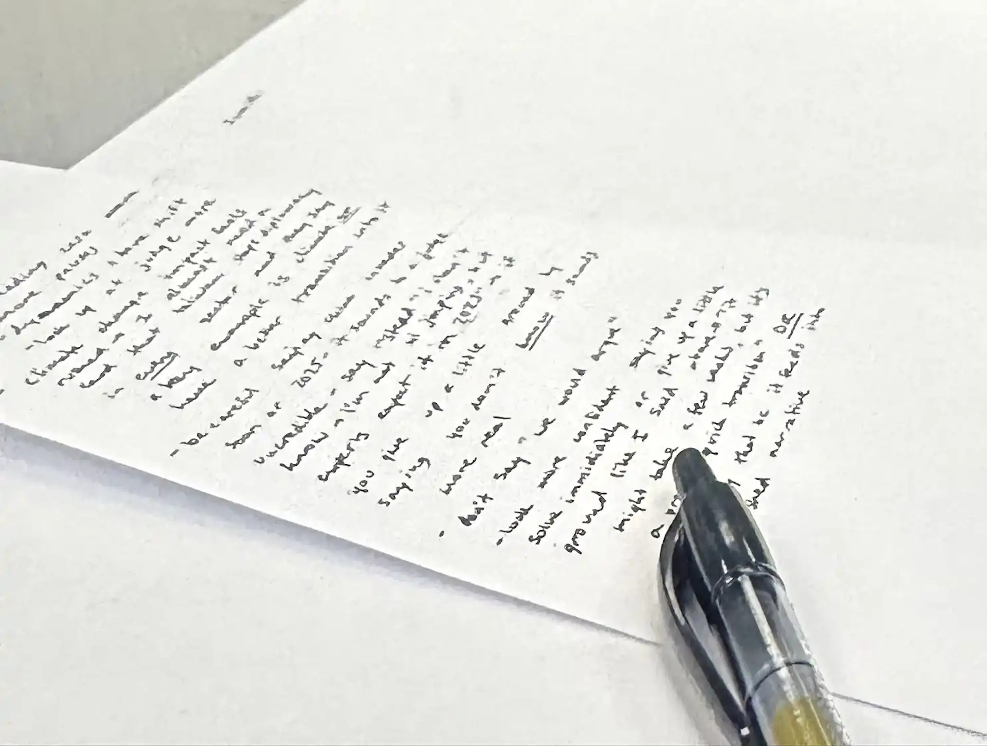 A paper with a pen on it, in the background, two students lean over a laptop