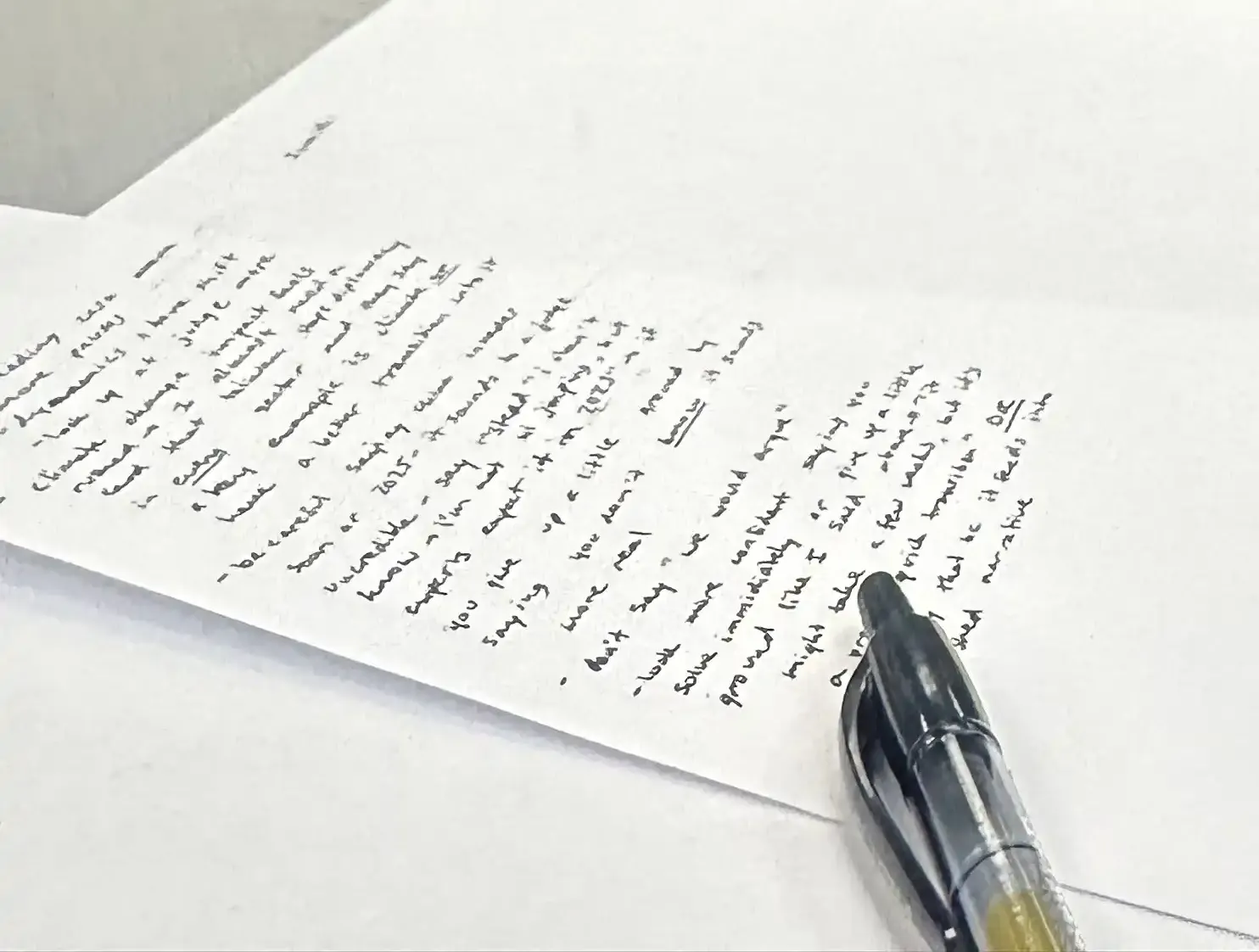 A paper with a pen on it, in the background, two students lean over a laptop