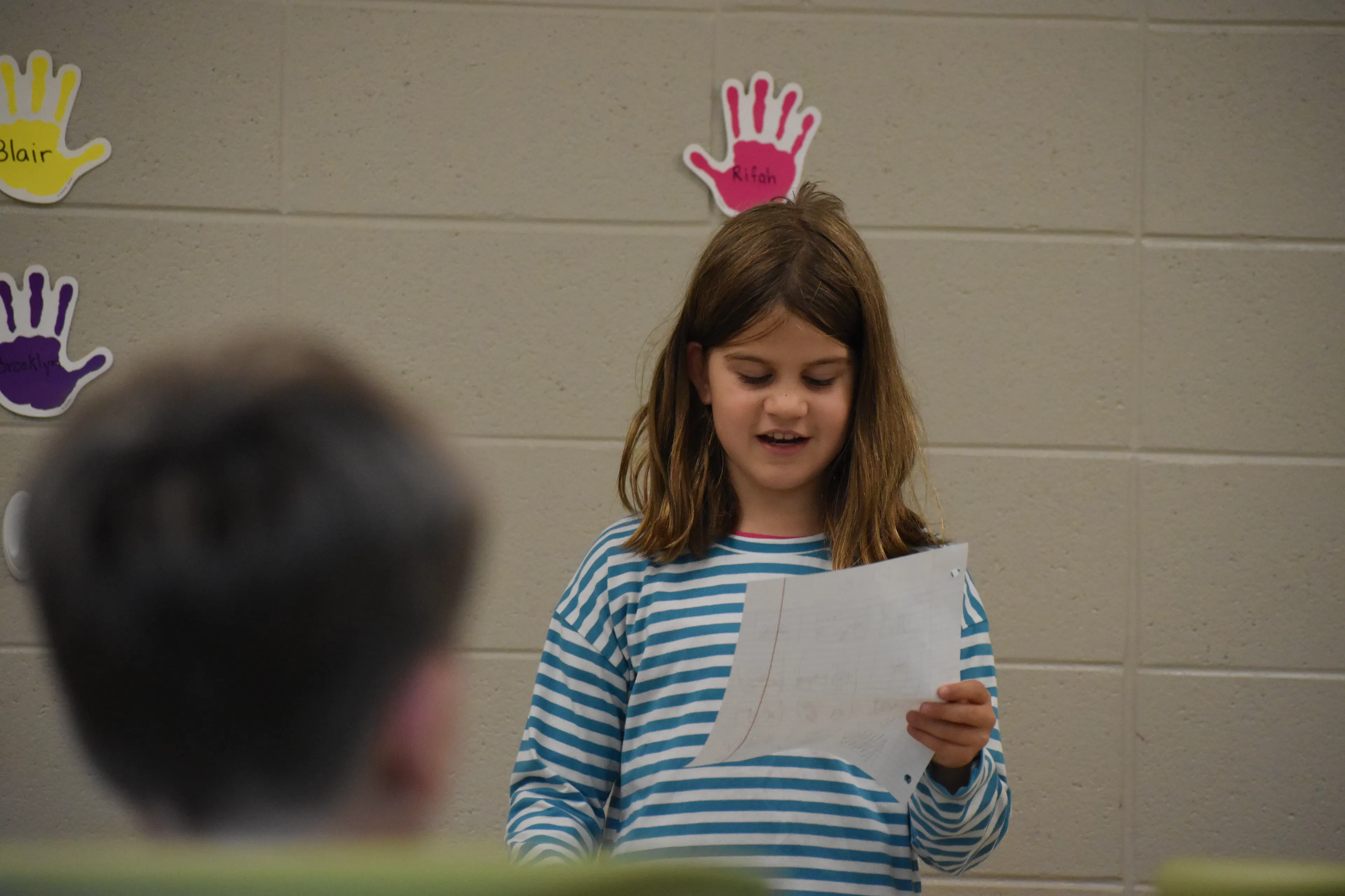 A young girl reads from a paper giving a speech