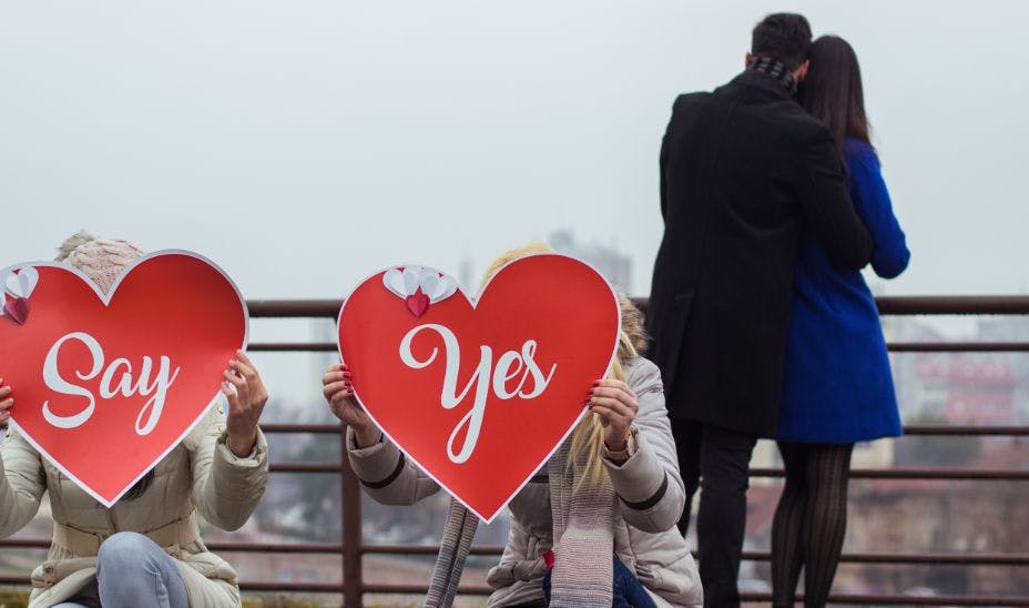 a surprise proposal with signs "Say yes"