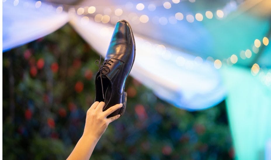 a bride's hand holding groom's shoe