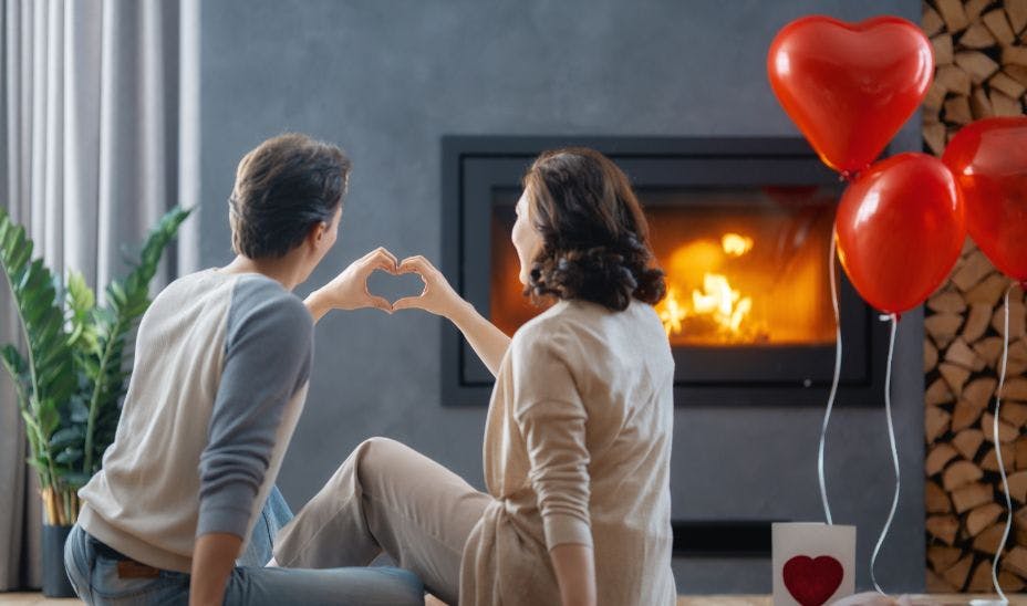 a couple celebrating valentines day with balloons sitting next to a fireplace