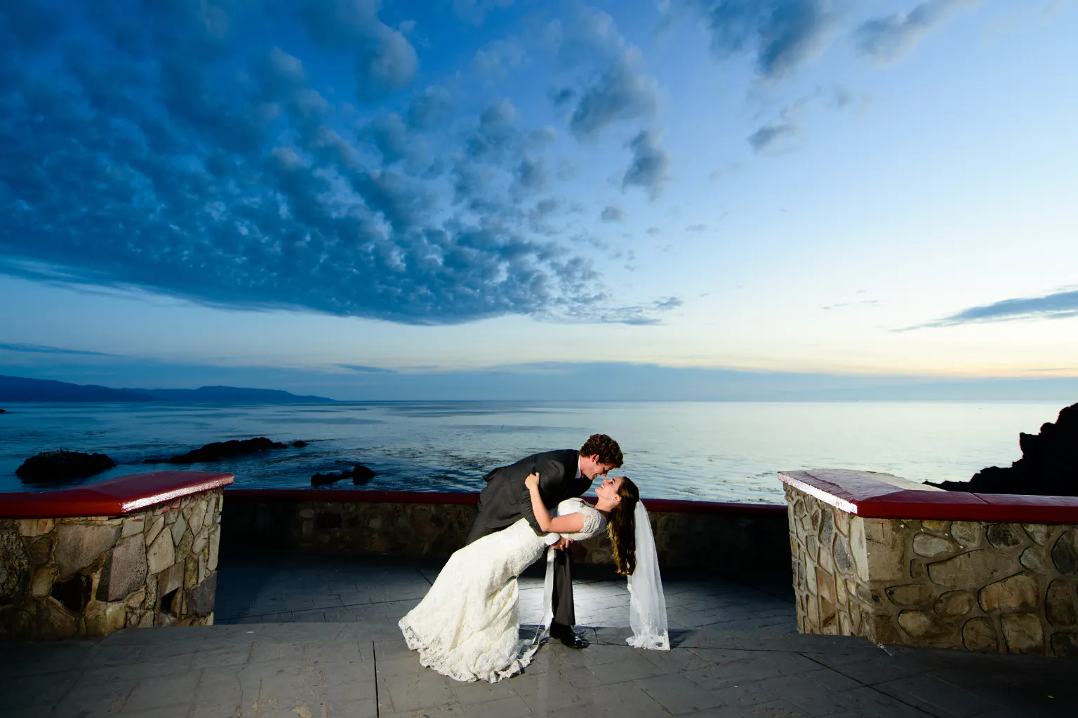 A newlywed couple shares a romantic dip by the ocean at sunset, ideal inspiration for the travel-loving bride.