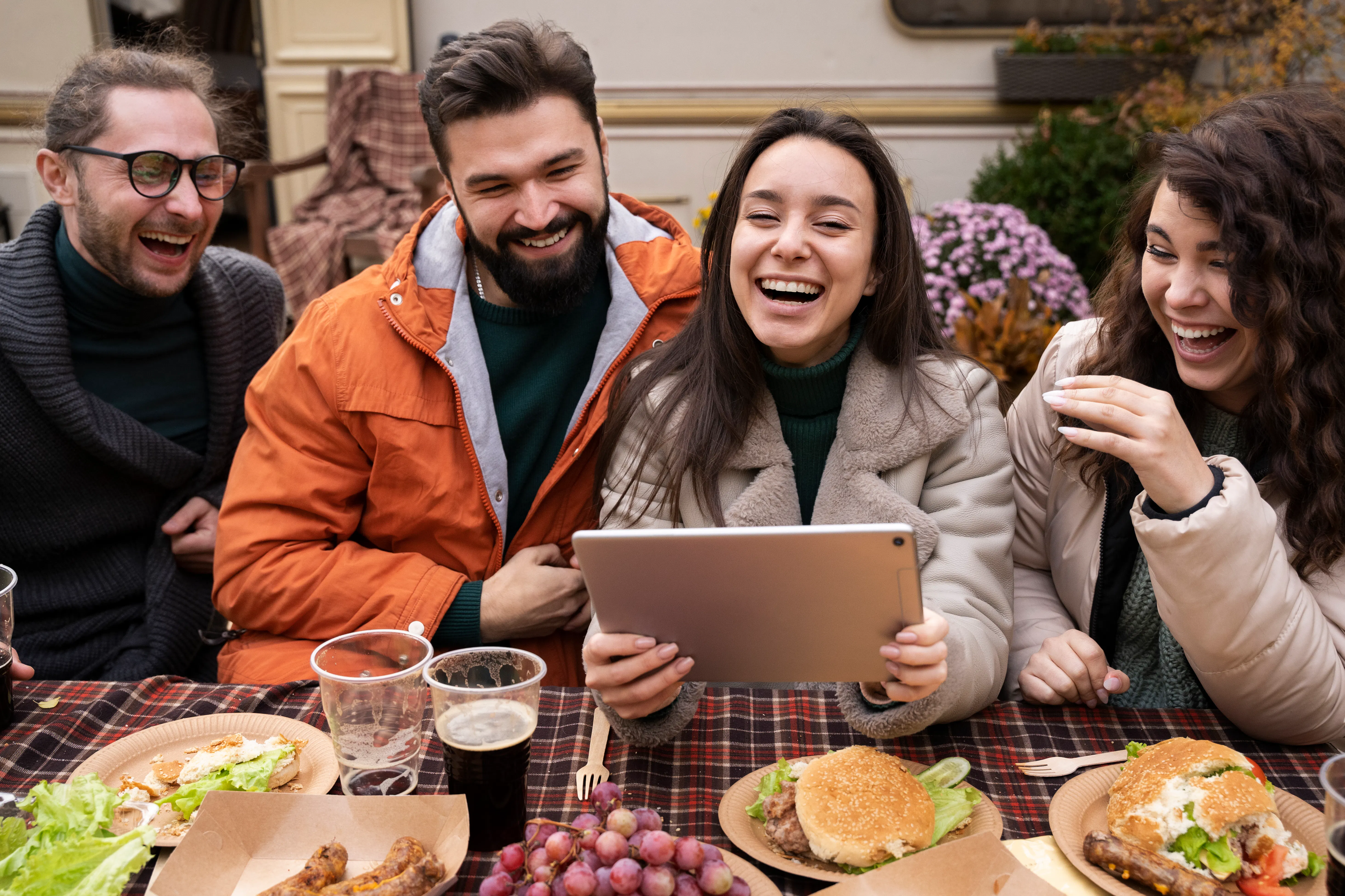 Group of friends at work laughing together while eating outdoors.