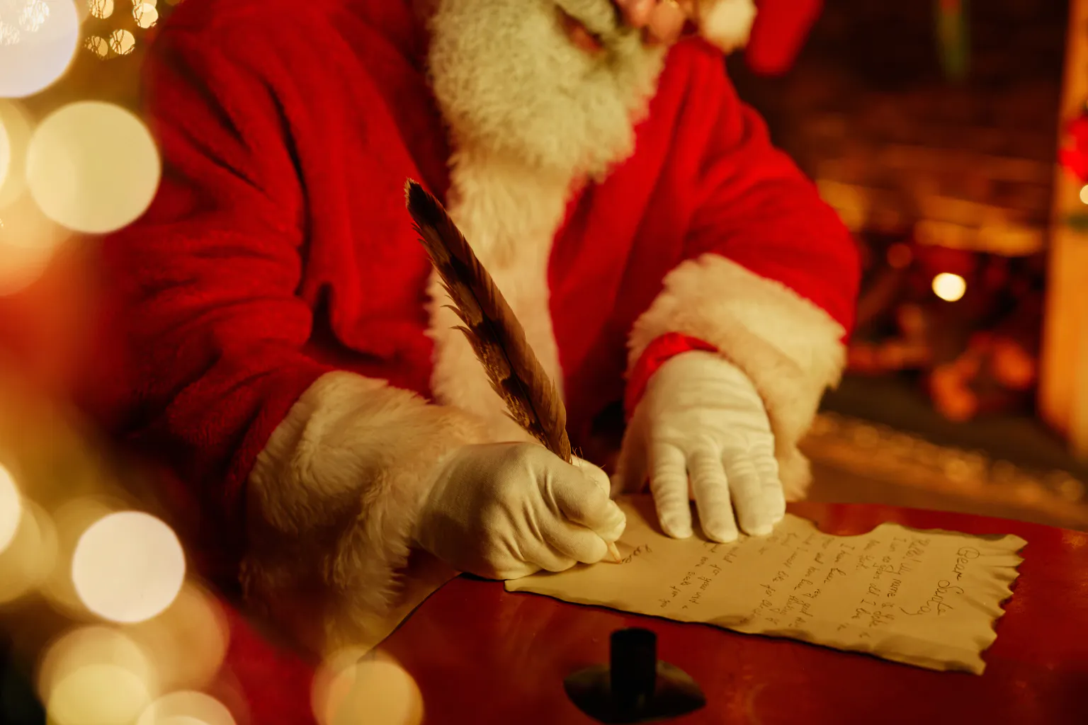 Santa writing a personalized Christmas letter with a quill.