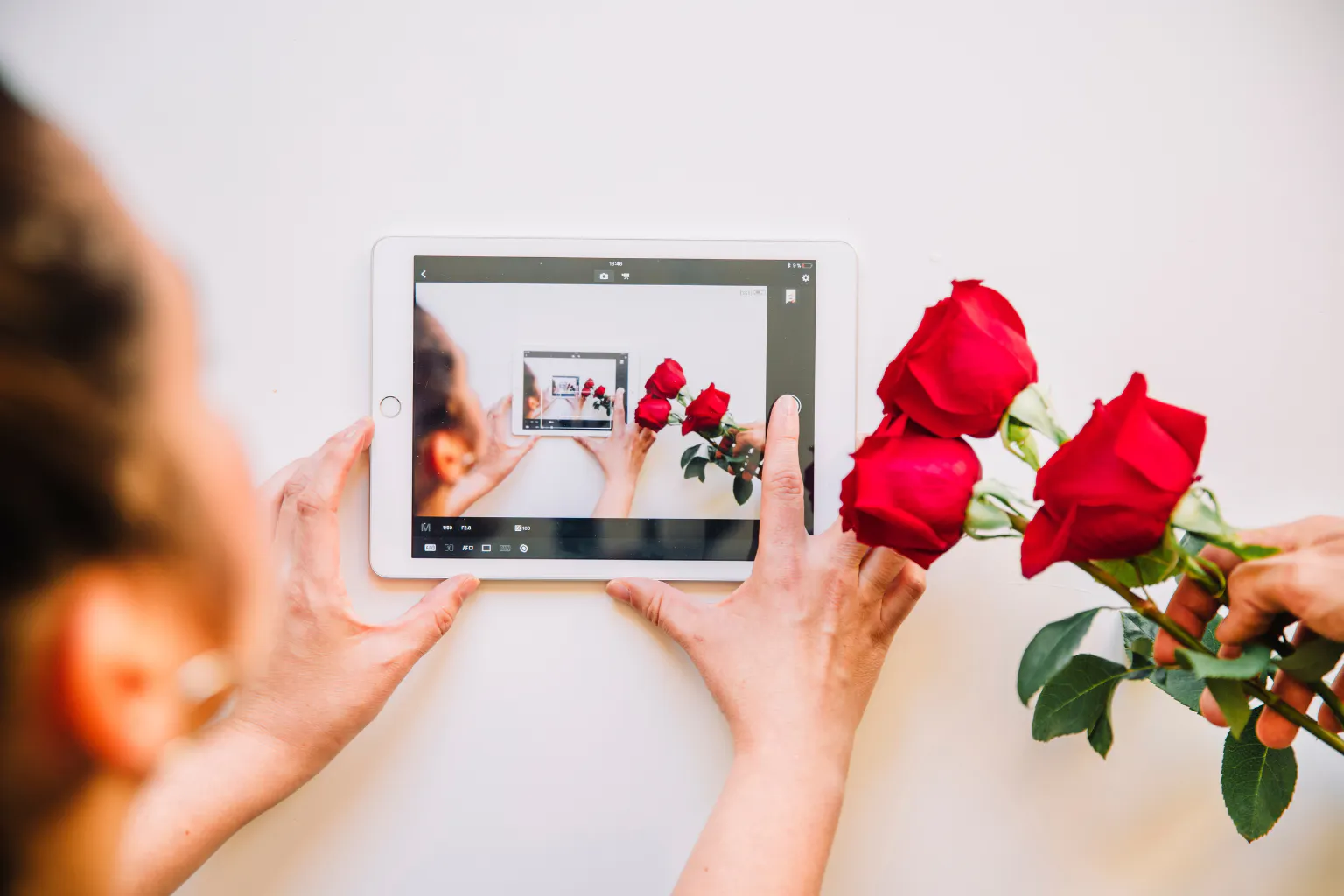Person capturing roses with a tablet, blending creativity and tech in gift-making.
