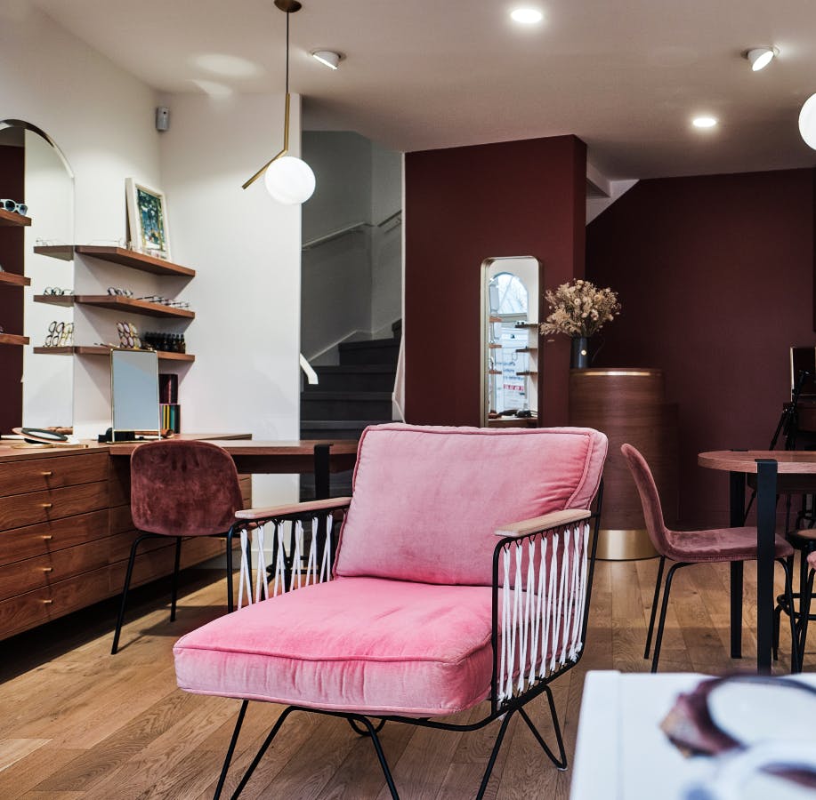 intérieur boutique Célestin lunetier avec fauteuil rose étagères et meubles bois 