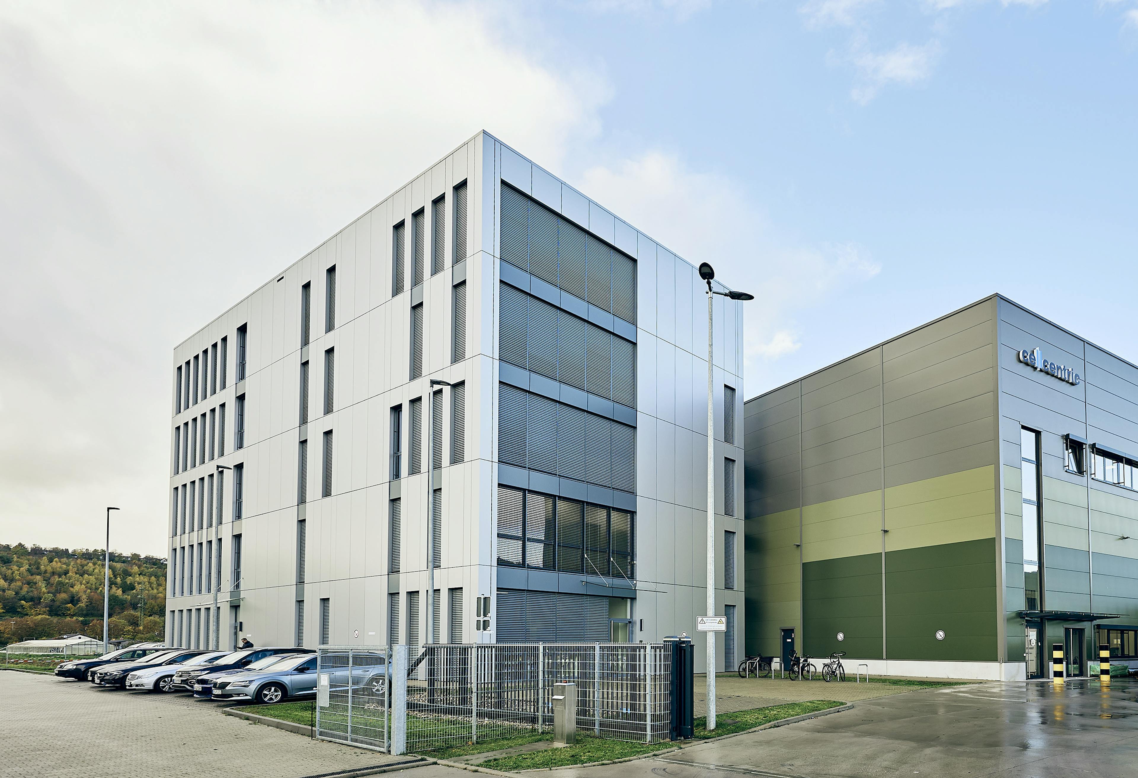 Office and production building with parked cars and bicycles in front of the entrance.