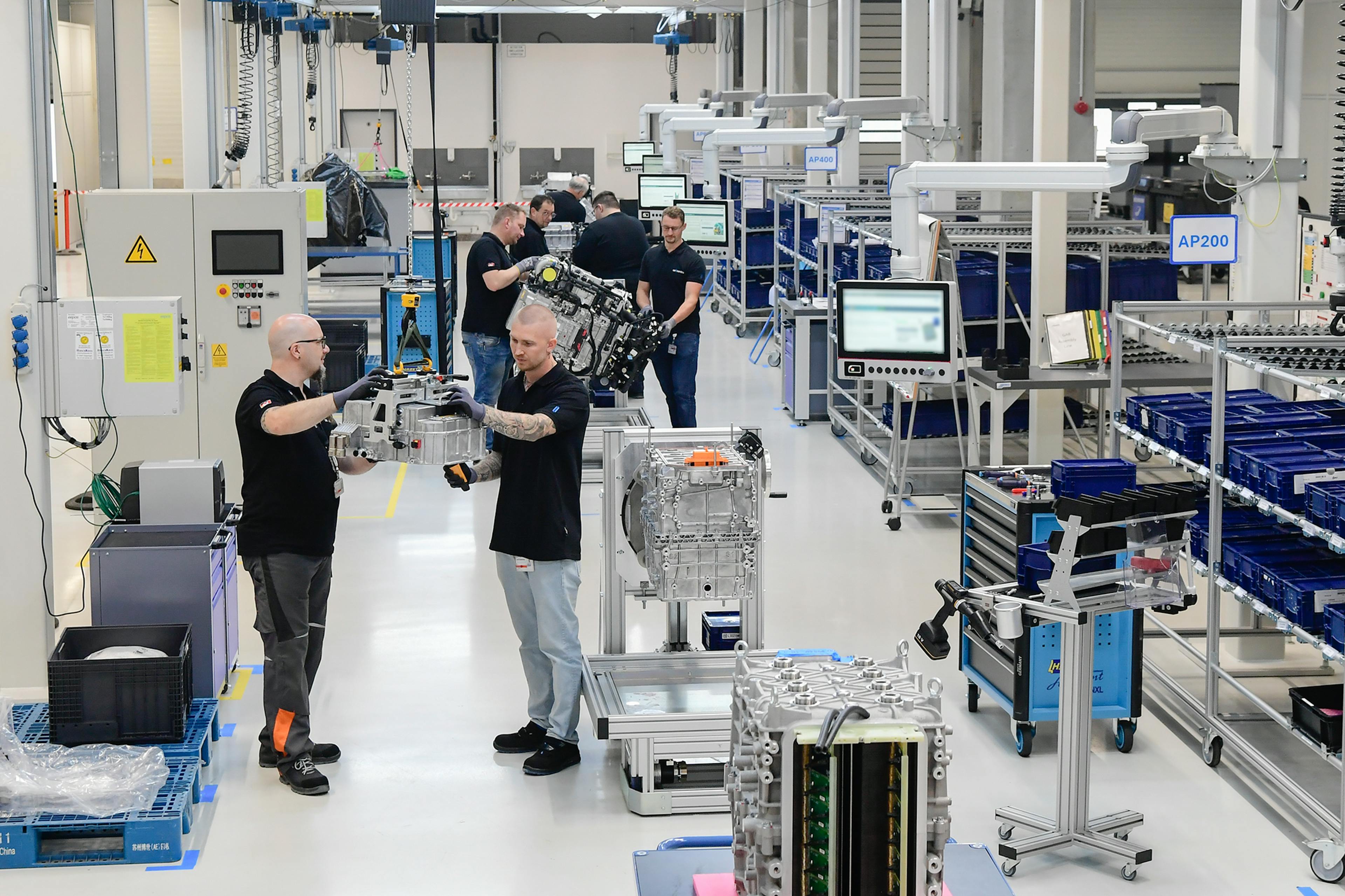 Employees assemble drive units in a modern, well-organized production hall.
