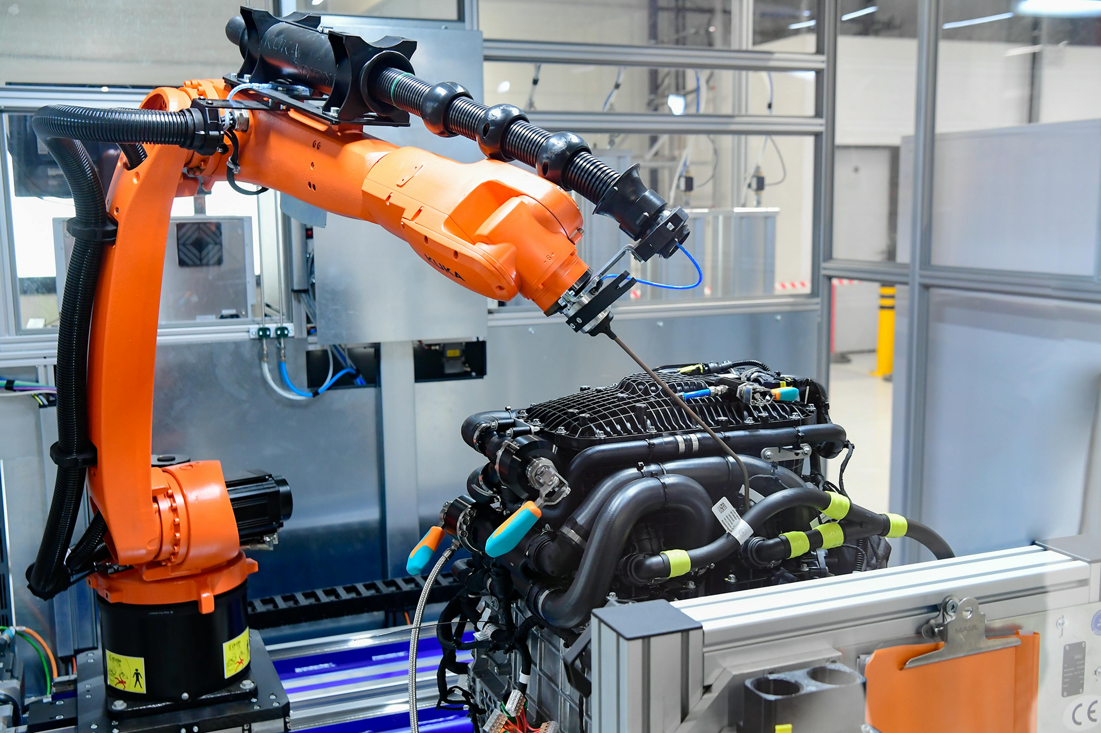 Industrial robot processes complex engine module in an automated production cell.