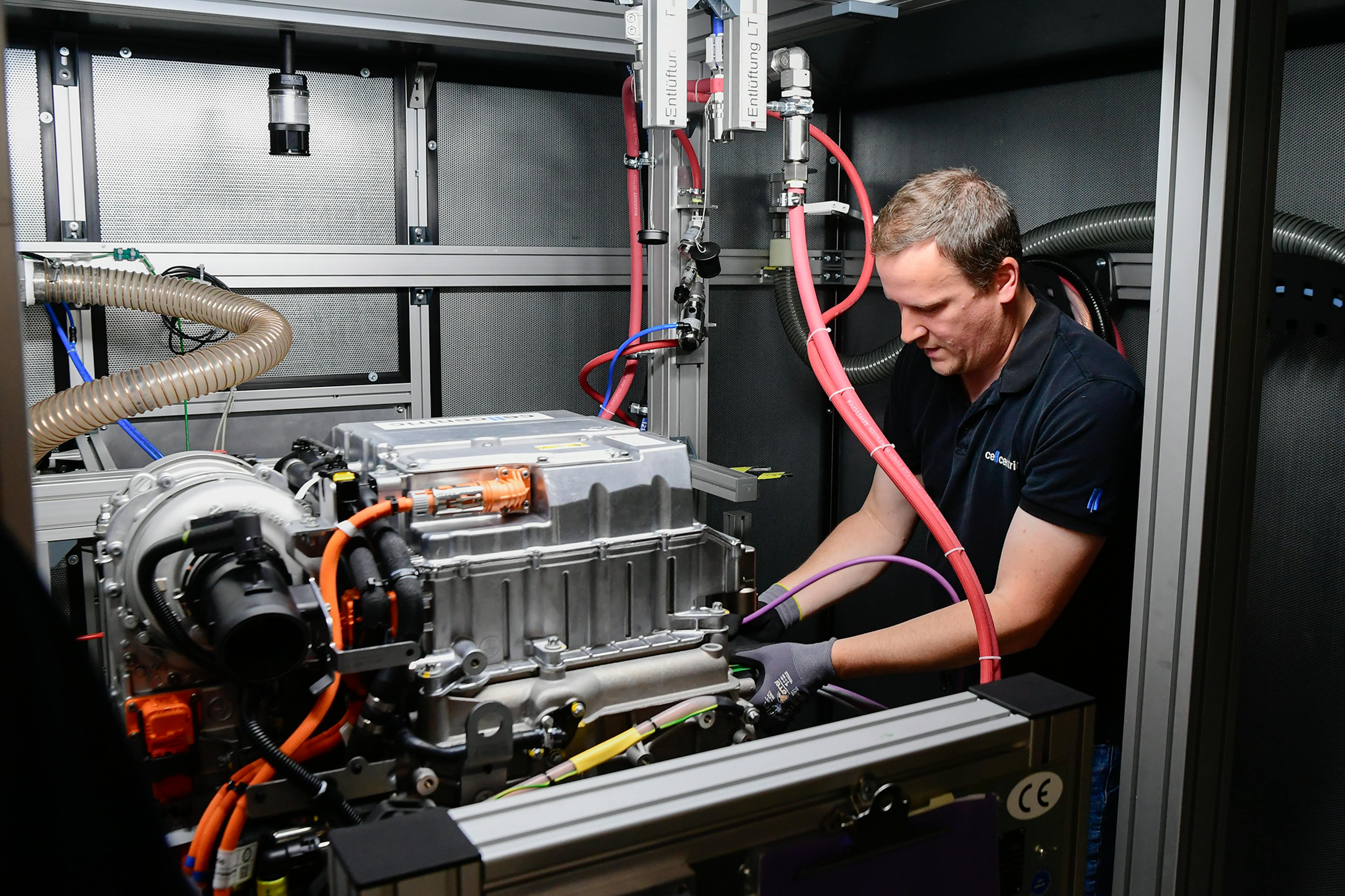 Technician works on complex test rig with cables and drive components.