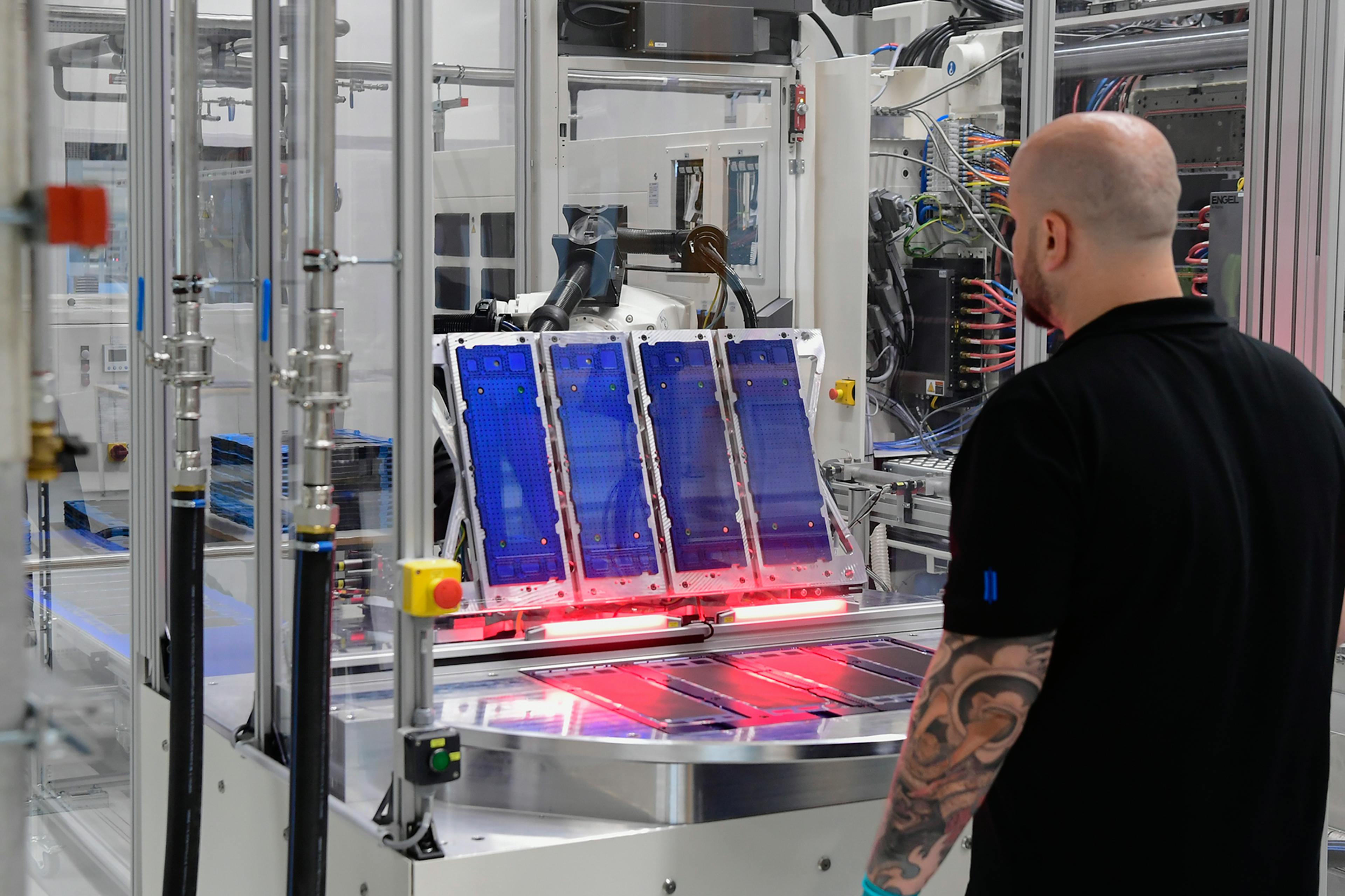 Employee monitors automated production system with blue-lit modules.