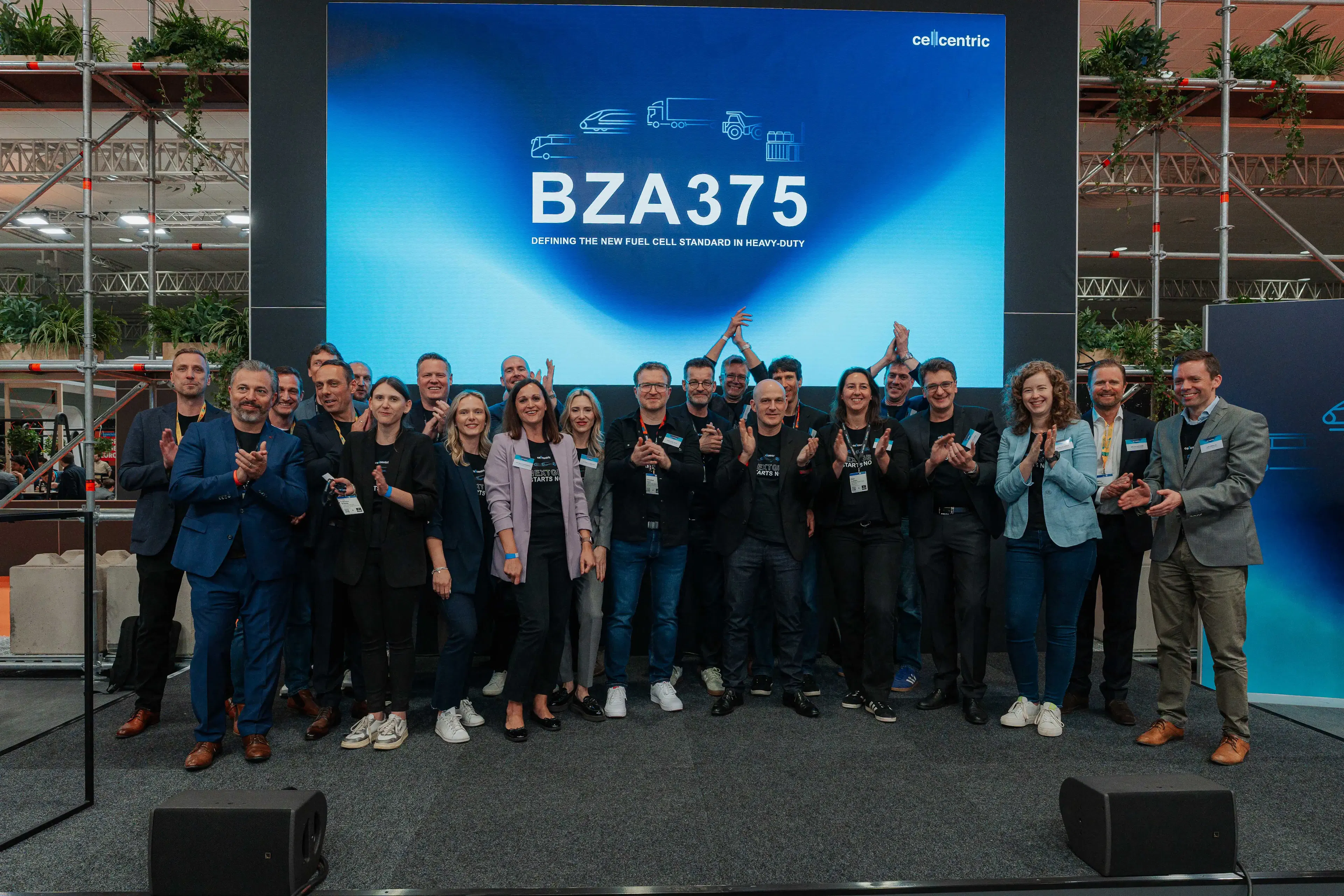 Project team applauds in front of a screen bearing the “BZA375” logo